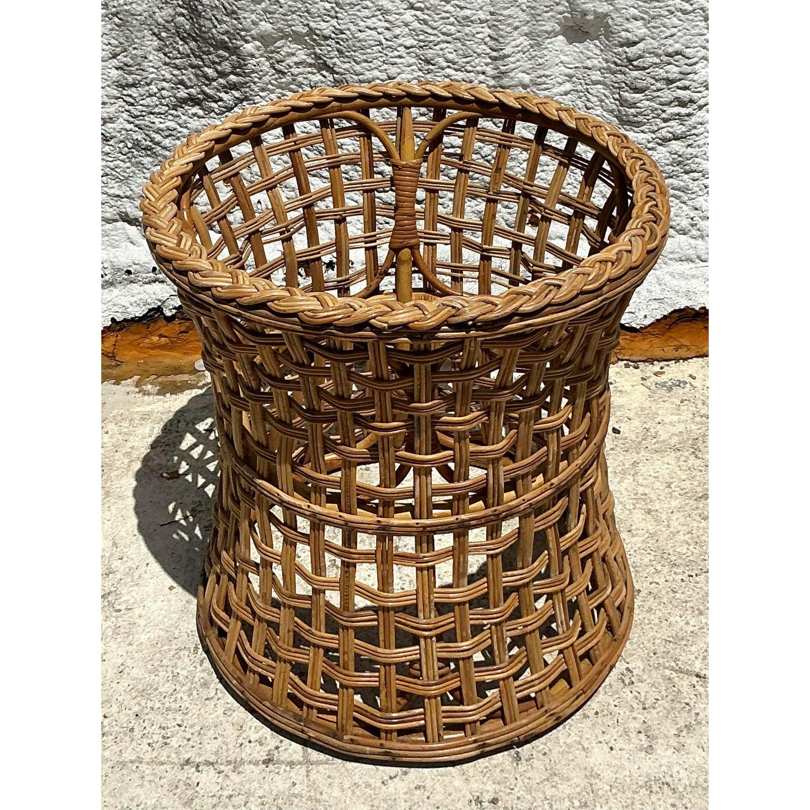 Introduci un tocco audace di texture naturale e fascino costiero nel tuo spazio con questo sostanzioso piedistallo da tavolo in rattan intrecciato vintage. Questo pezzo, sapientemente intrecciato a mano, è caratterizzato da un robusto design a