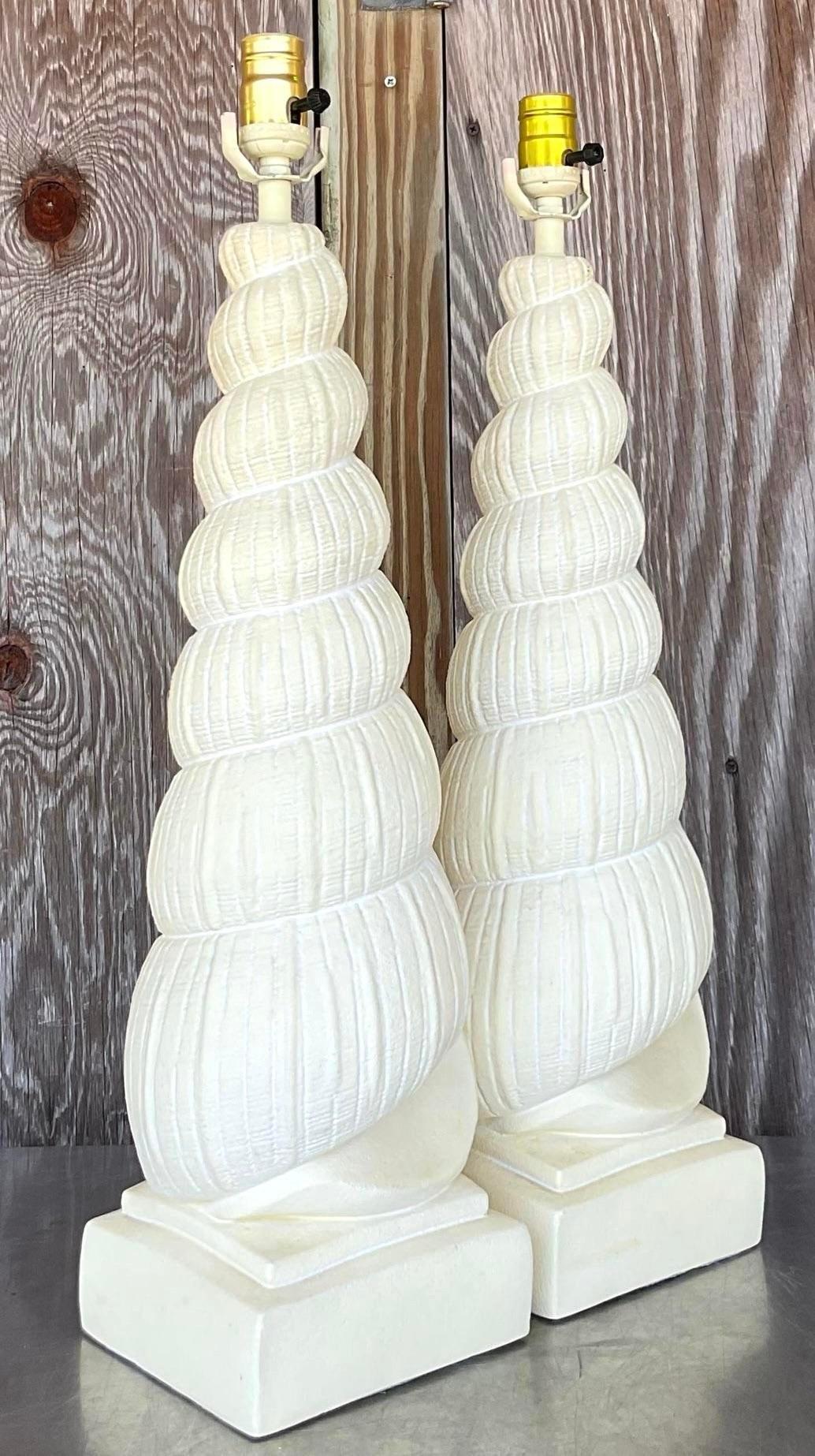 Add a coastal touch to your décor with this pair of vintage coastal plaster tall shell lamps. Combining coastal charm with American craftsmanship, these lamps showcase intricate shell designs, bringing a beachy elegance to any space with timeless