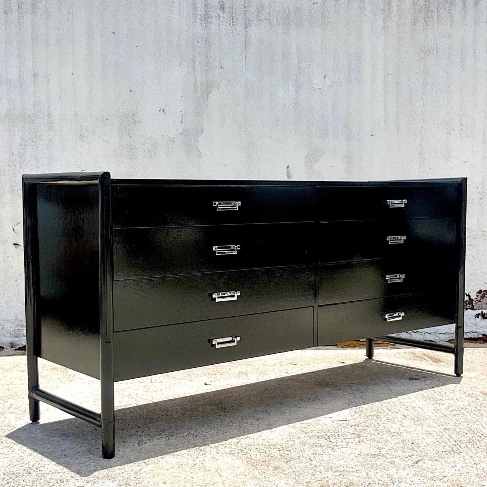 A stunning vintage Coastal dresser. Made by the iconic McGuire group. A beautiful black lacquered oak cabinet with rattan trim. Chrome plated handles. Matching nightstands also available. Acquired from a Palm Beach estate.
