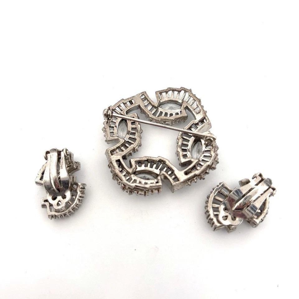 This vintage fashion jewelry set includes a large cushion-shaped brooch and matching clip-on earrings, featuring brilliant imitation white diamonds, likely cubic zirconia (CZ), set in plated white metal. The earrings are stamped 