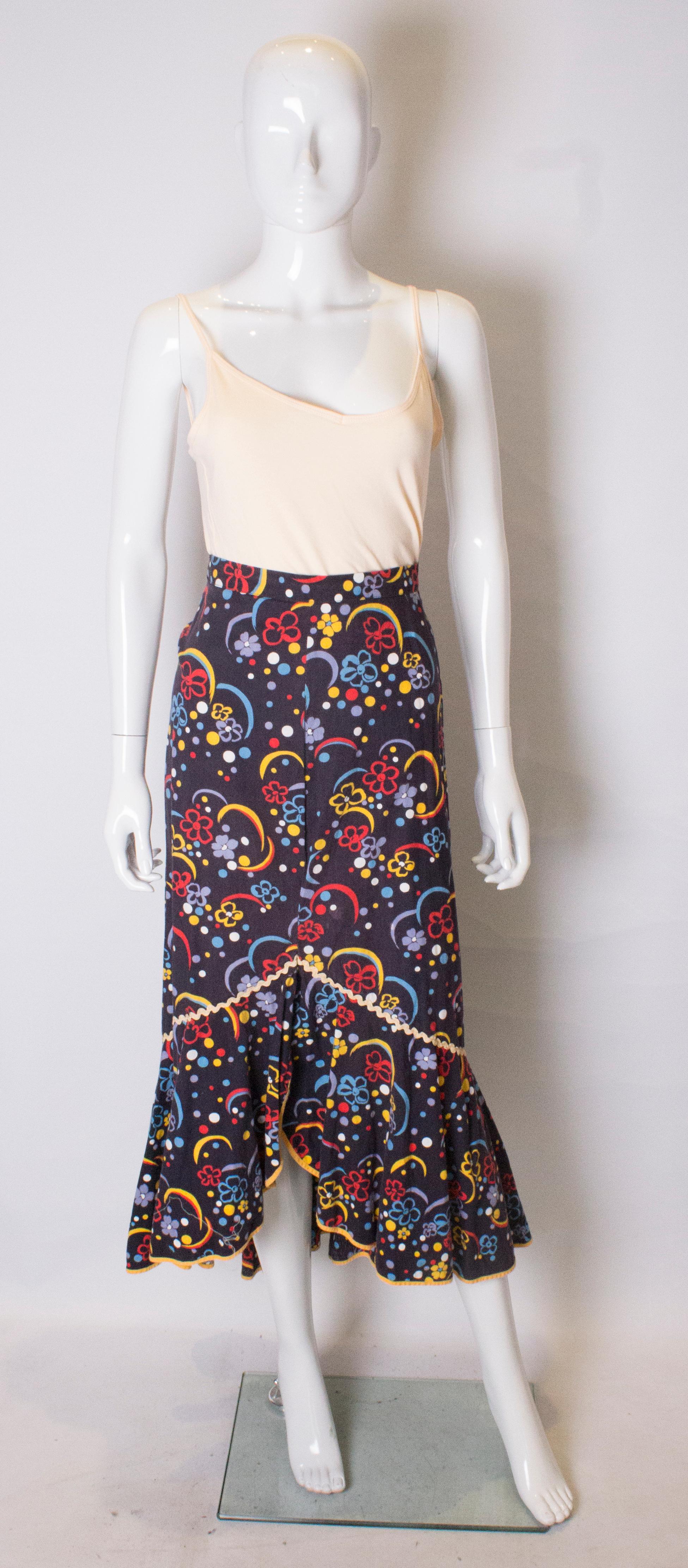 A great vintage cotton print skirt in a flamenco style. The skirt has a dark blue background with floral print, ivory trim on the body, and a large frill at the hem with a yellow trim.  It has a back central zip.
