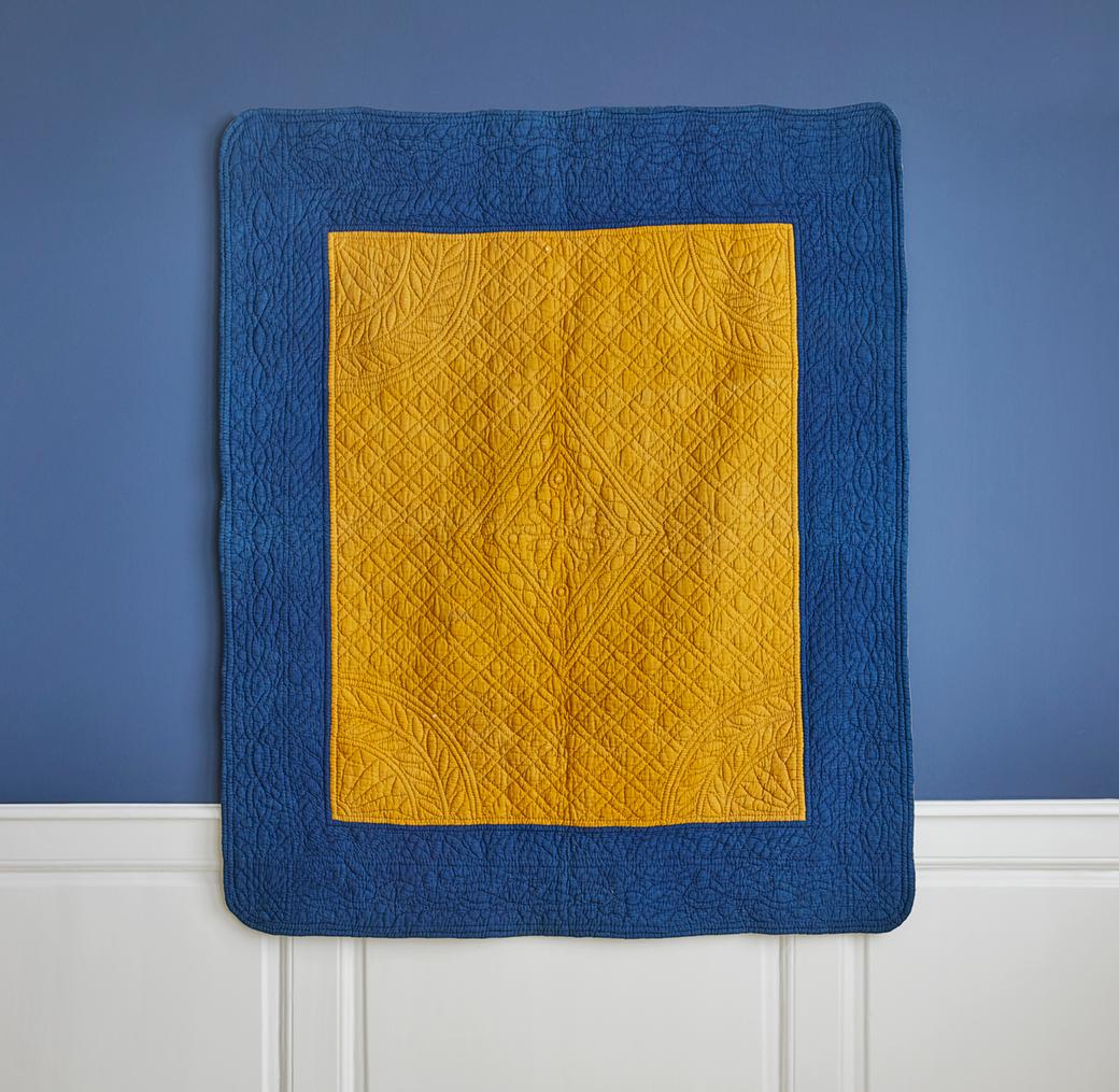 France, early 19th century

Cotton quilt with a border of a beautiful shade of indigo and the center a gorgeous saffron yellow. Simple stitched patterns of diamond shapes with a flower motif at the center. Back in a blockprinted cotton with small