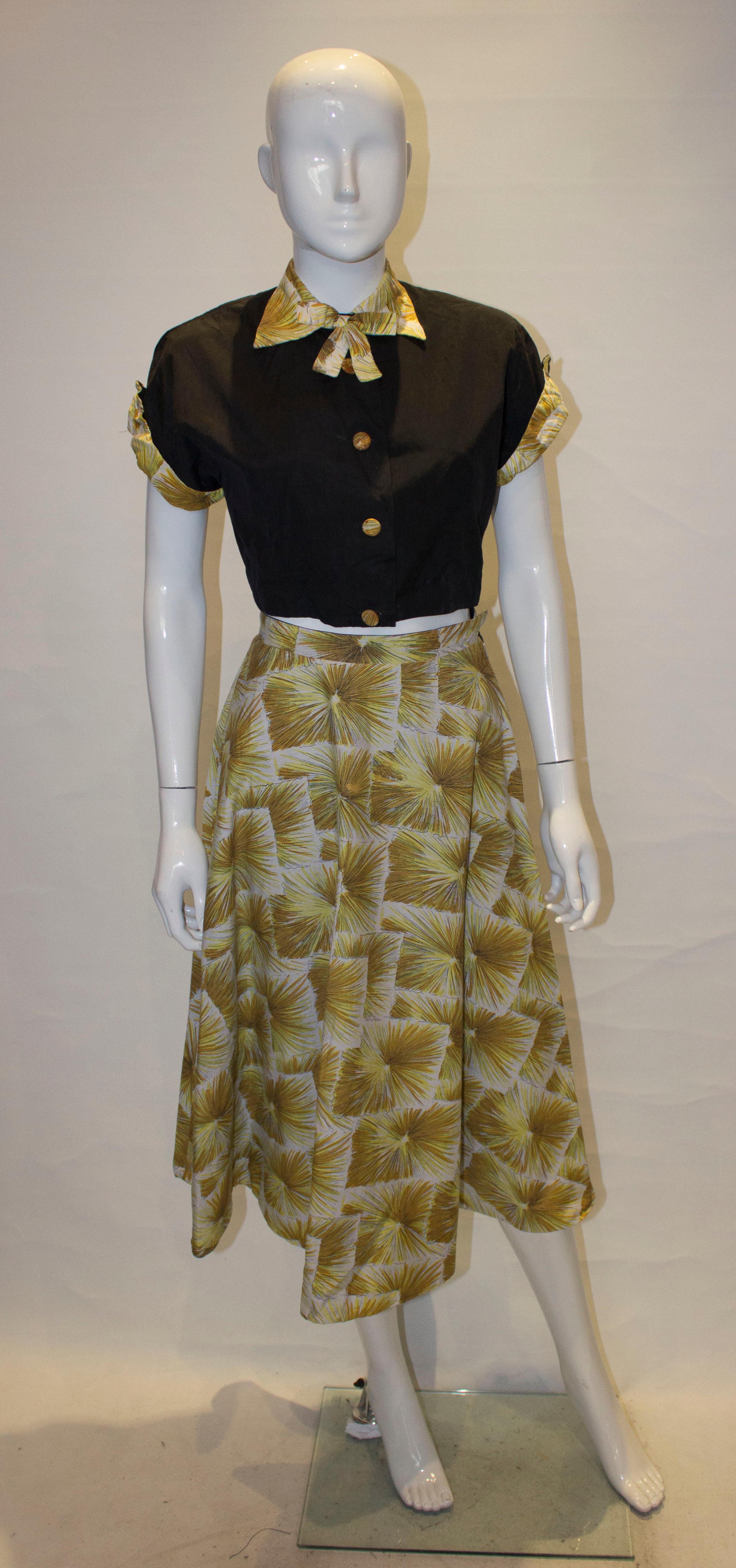 A vintage outfit with the benefit of a reversible skirt.  The skirt is black on one side and print on the  other.  The top is black with print covered buttons and collar. 
Measurements: Skirt waist 23'', length 32'' Top bust 36'', length 16''