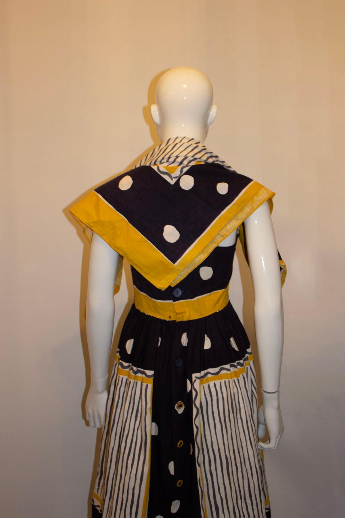 Ein wunderschönes Vintage-Sonnenkleid aus Baumwolle von Sambo of London. Das Kleid ist in einer wunderschönen Farbkombination aus Blau, Weiß, Senf und Grau gehalten. Es hat tolle Taschendetails auf der Vorderseite und eine Knopföffnung auf der
