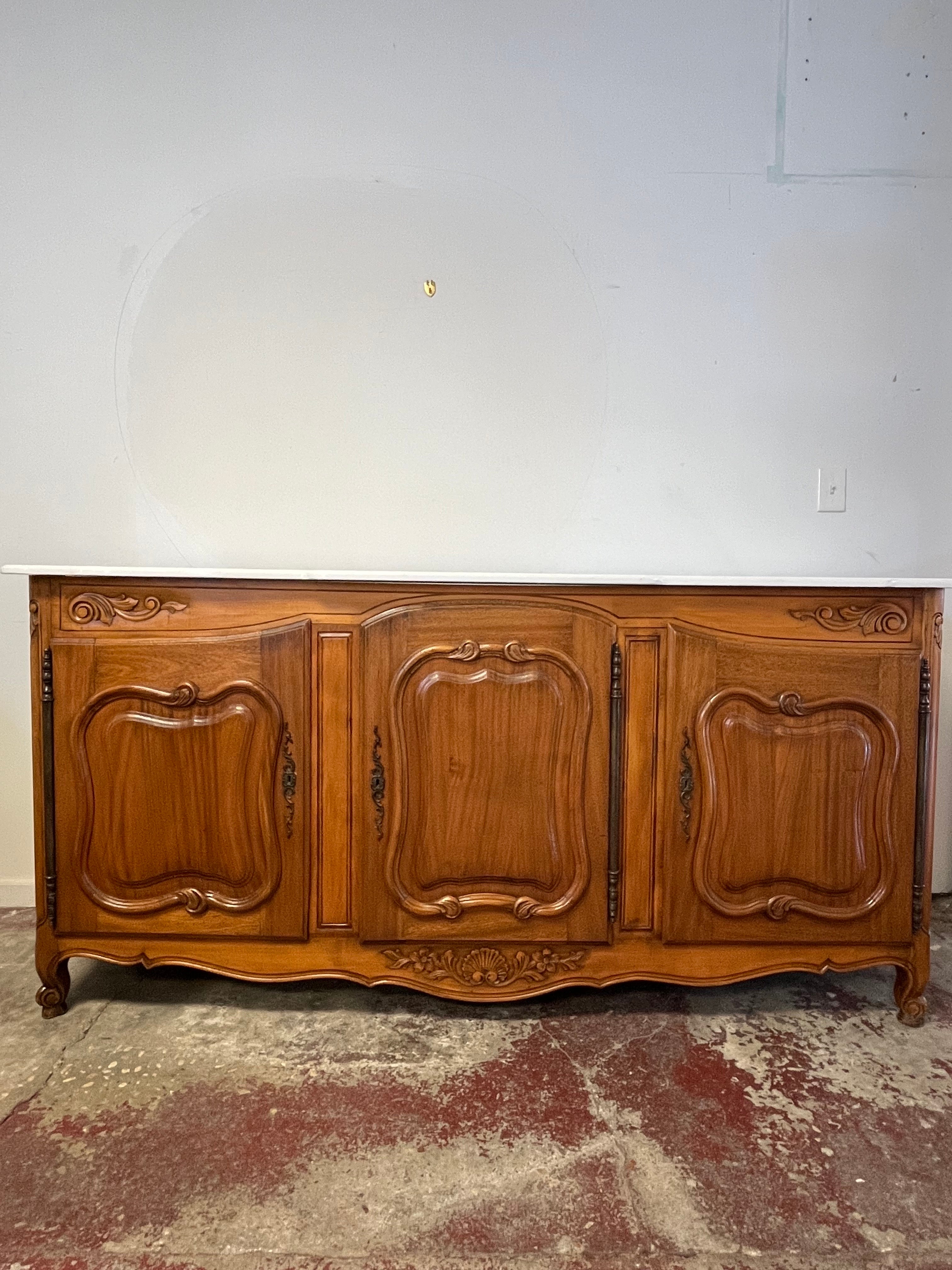 Il buffet country francese d'epoca con piano in marmo in noce è un classico esempio di sobria eleganza! Realizzata in noce con una bella venatura, presenta una sezione centrale a gradini, raffinati dettagli modanati intorno ai pannelli delle porte,