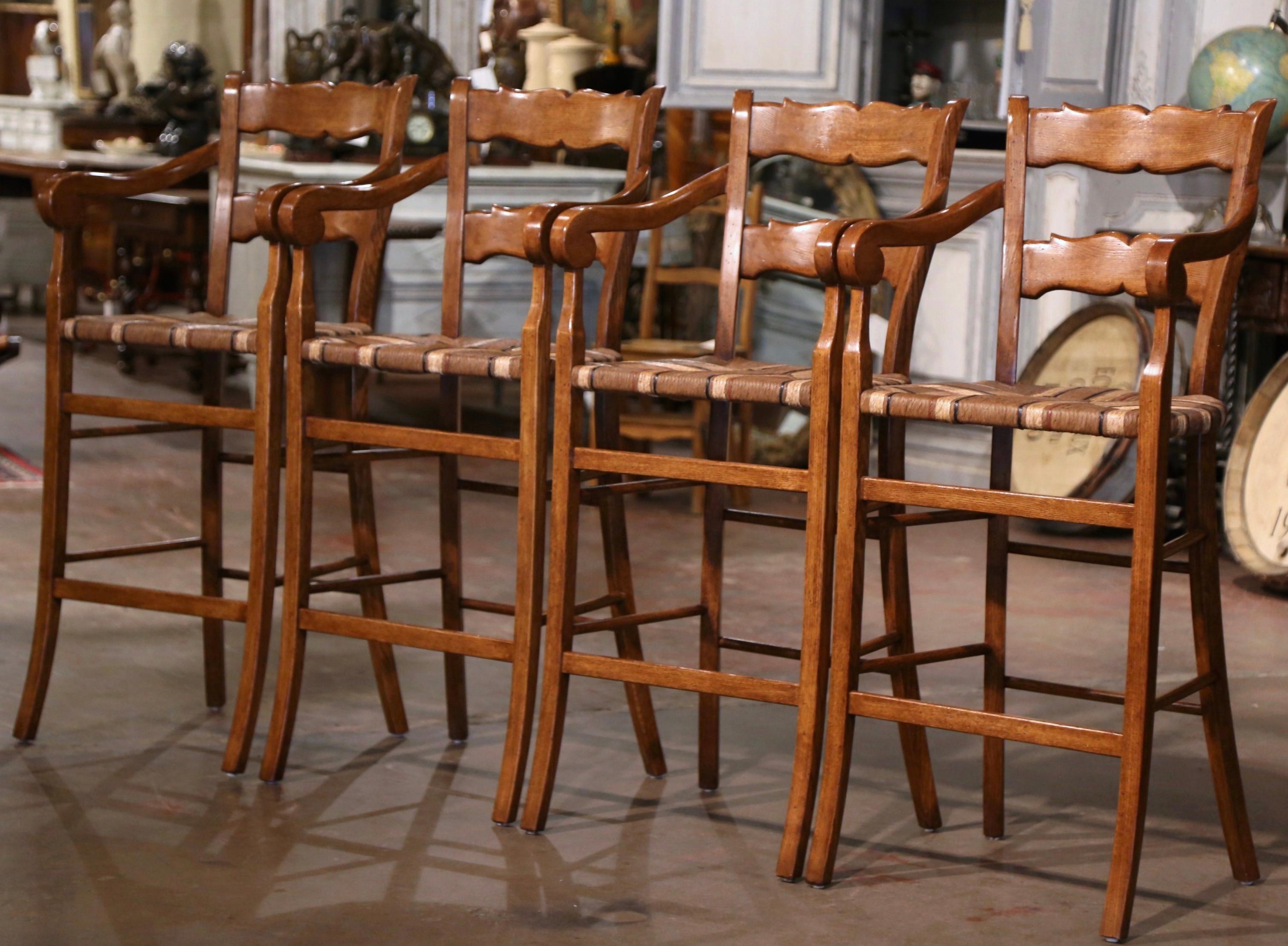 Habillez un bar avec cet élégant ensemble de tabourets fauteuils vintage. Sculptée à la main dans du bois de chêne en Normandie, France, vers 1990, chaque chaise repose sur des pieds en volute, au-dessus d'un double châssis inférieur. Le dossier