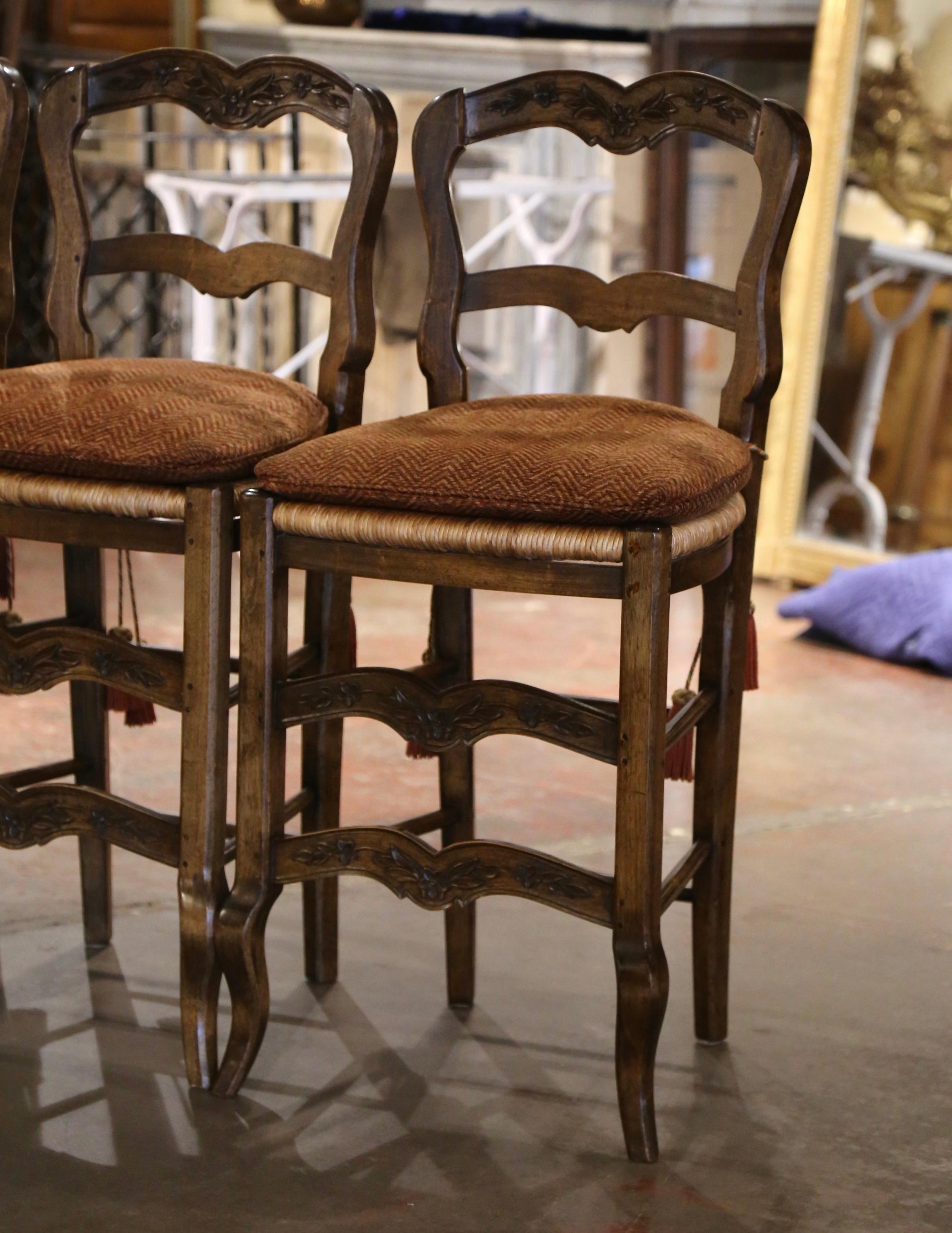 Dress a kitchen or bar counter with this elegant set of vintage stools. Hand carved from walnut wood in Normandy France circa 1980, each Provincial chair stands on front curved legs decorated with a double scalloped bottom stretcher embellished with