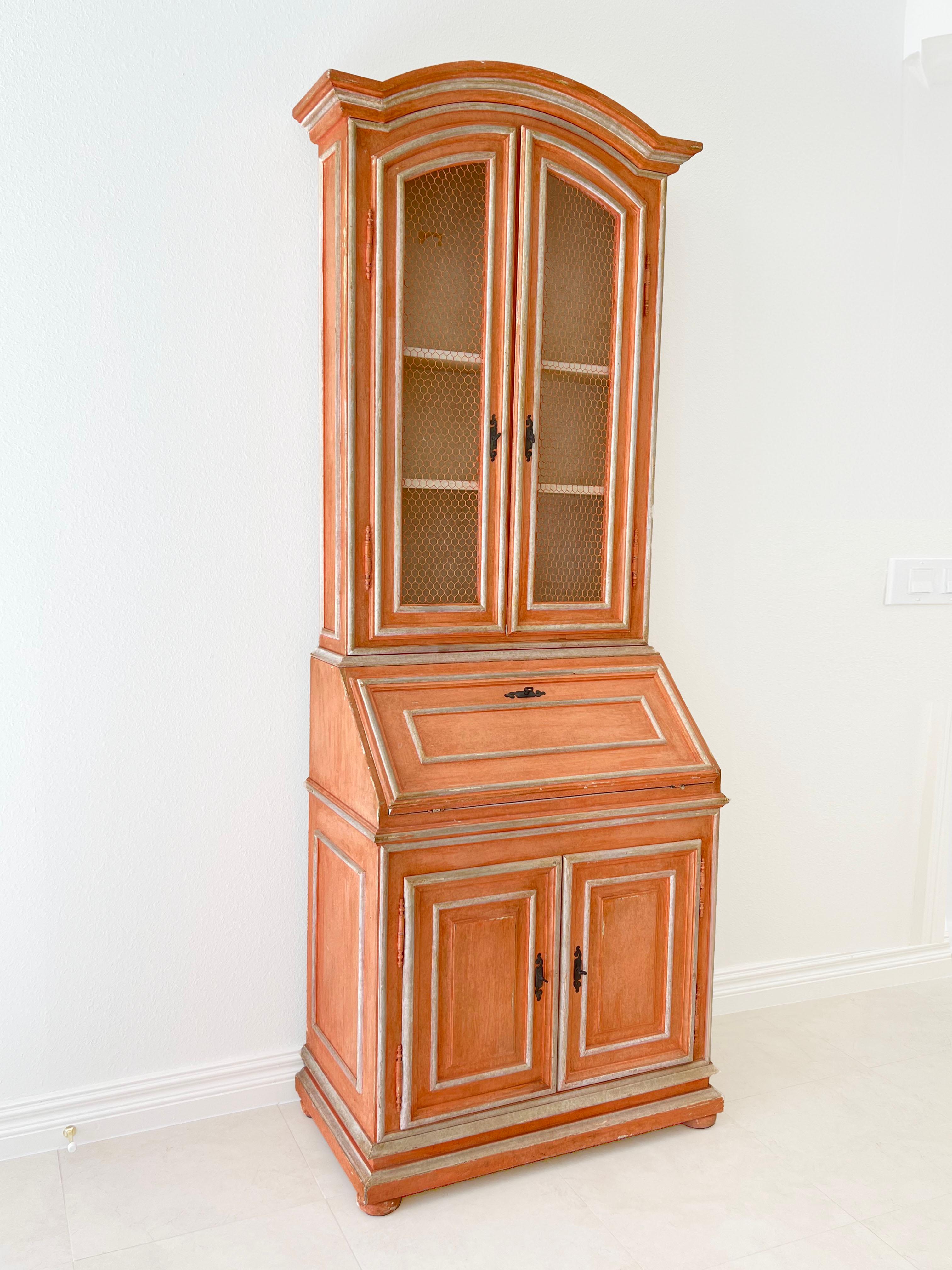 Este elegante escritorio alto de secretaria de estilo rural francés con molduras y puertas de rejilla tiene un precioso acabado de imitación en el interior y el exterior. A pesar de las pequeñas pérdidas y desgastes típicos de su edad, la pieza se