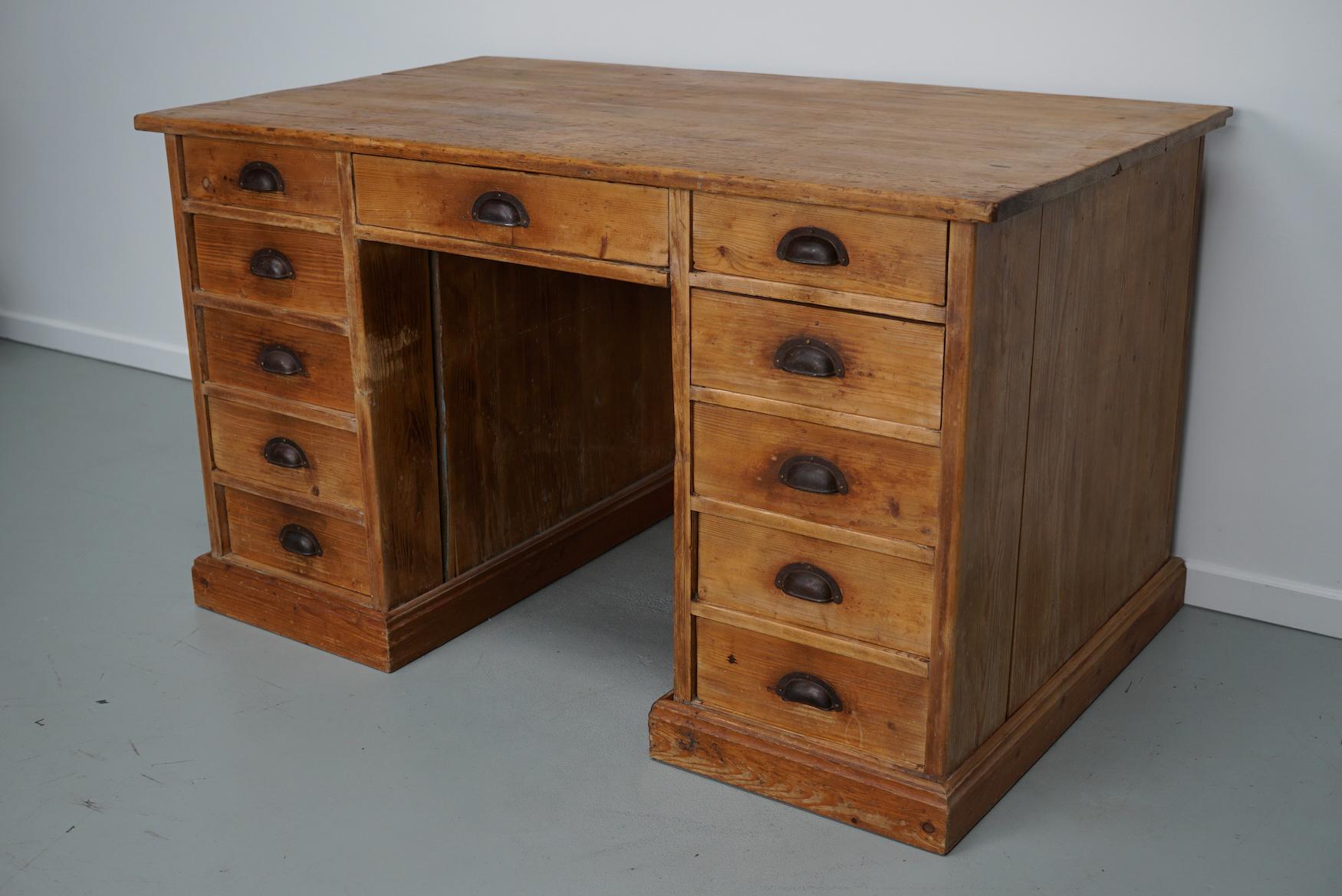 This desk was made around the 1930s in Germany. It is made from solid pine with many very deep drawers. The desk retained a very nice patina and signs of use over the years. The height to the worktop is 79.5 cm.