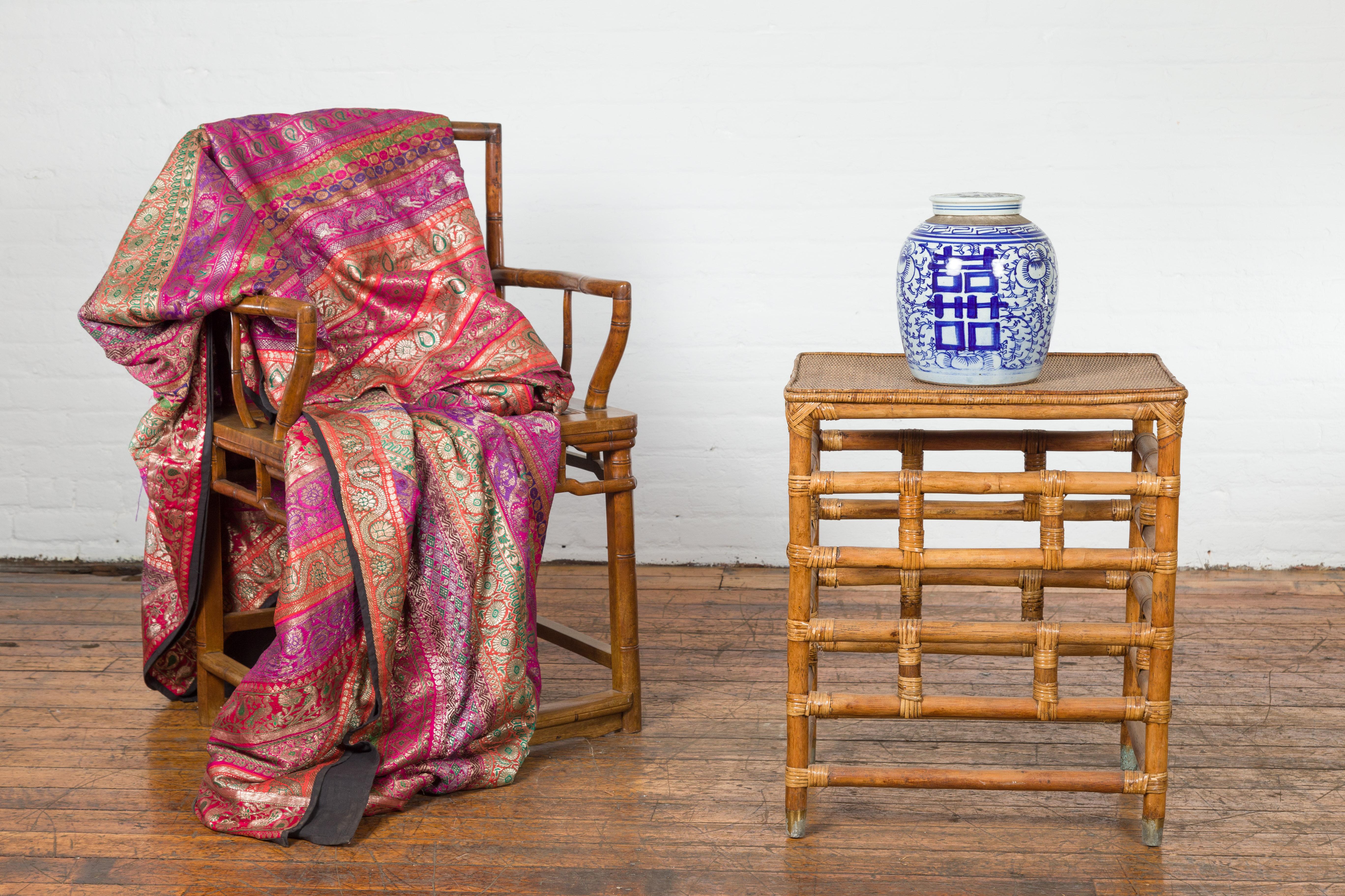 A vintage Burmese Country style bamboo side table from the Mid-20th Century, with hand woven rattan top, geometric base and patinated brass feet. Created in Burma (nowadays known as Myanmar) during the Midcentury period, this stylish side table