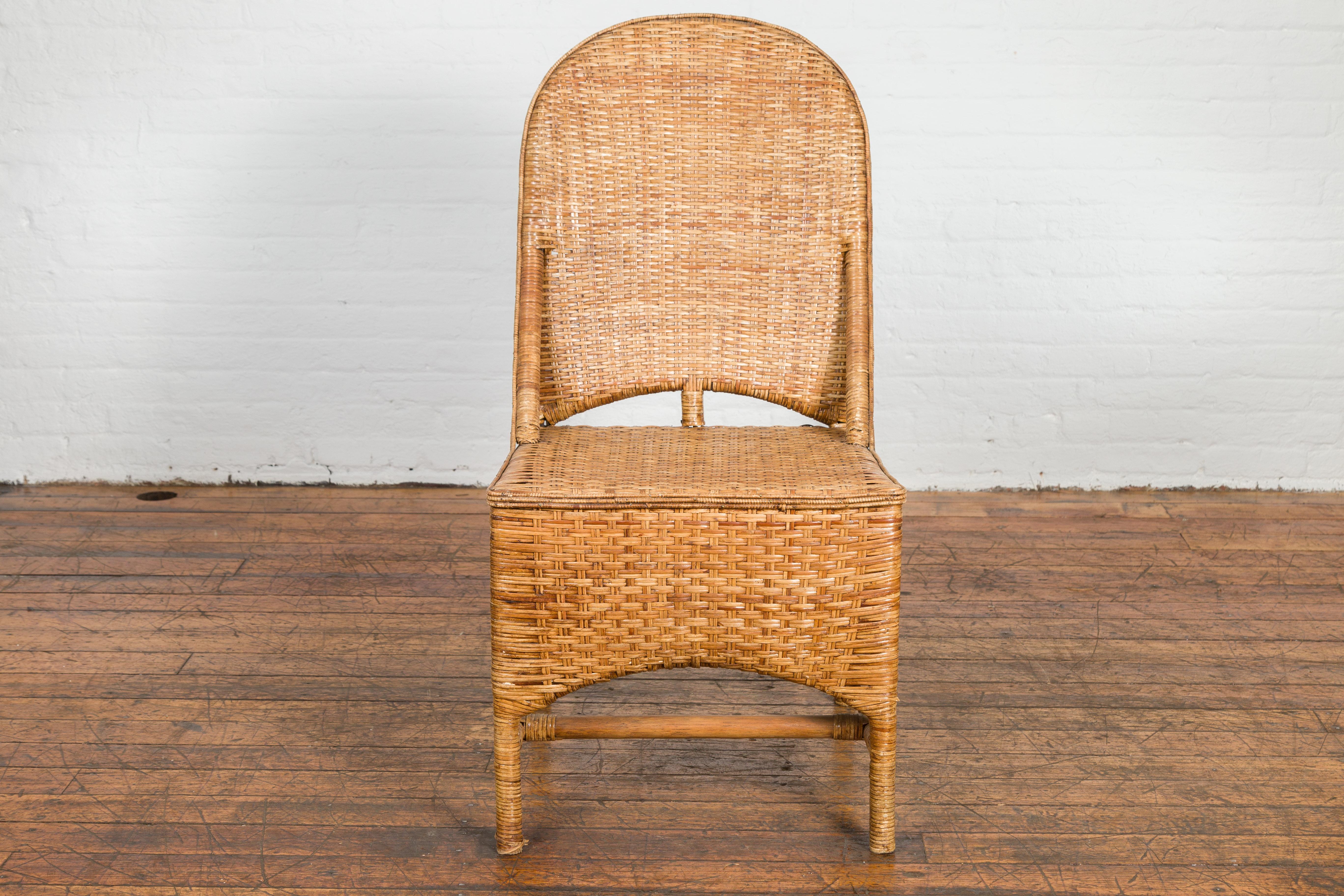 A vintage Country style Thai hand woven rattan chair from the mid 20th century, with arching back and double H-Form cross stretcher. Experience the essence of country living with this vintage Country-style Thai handwoven rattan chair from the