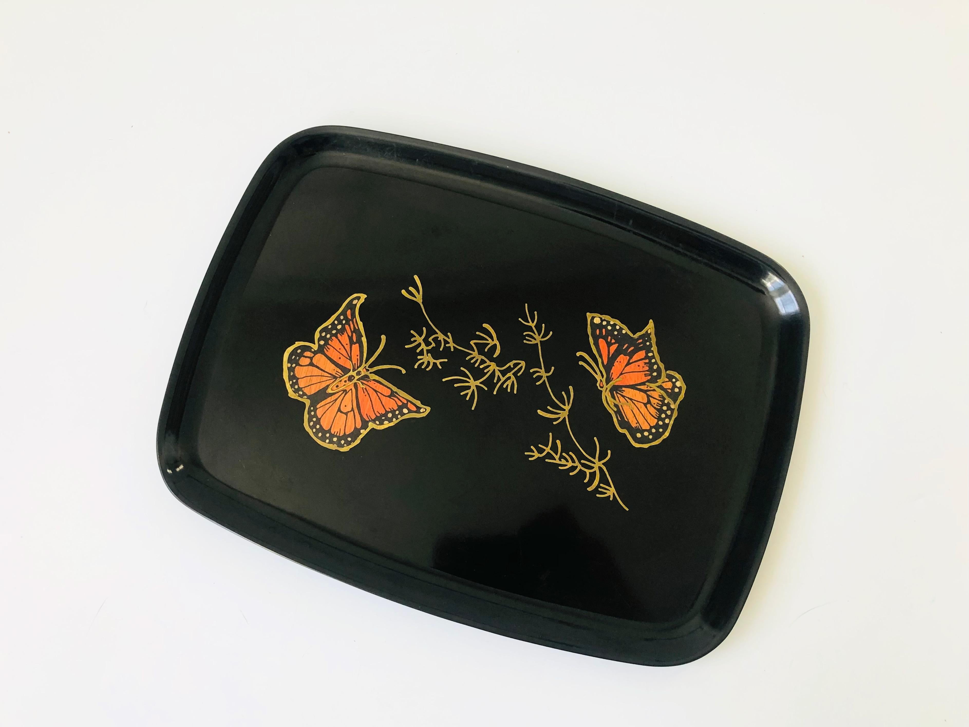 A wonderful vintage rectangular tray. The image s of butterflies in the center of the tray are formed from small pieces of inlaid shells, coins, woods, and metals fused into a satin black durable plastic-like material called phenolic. Made in