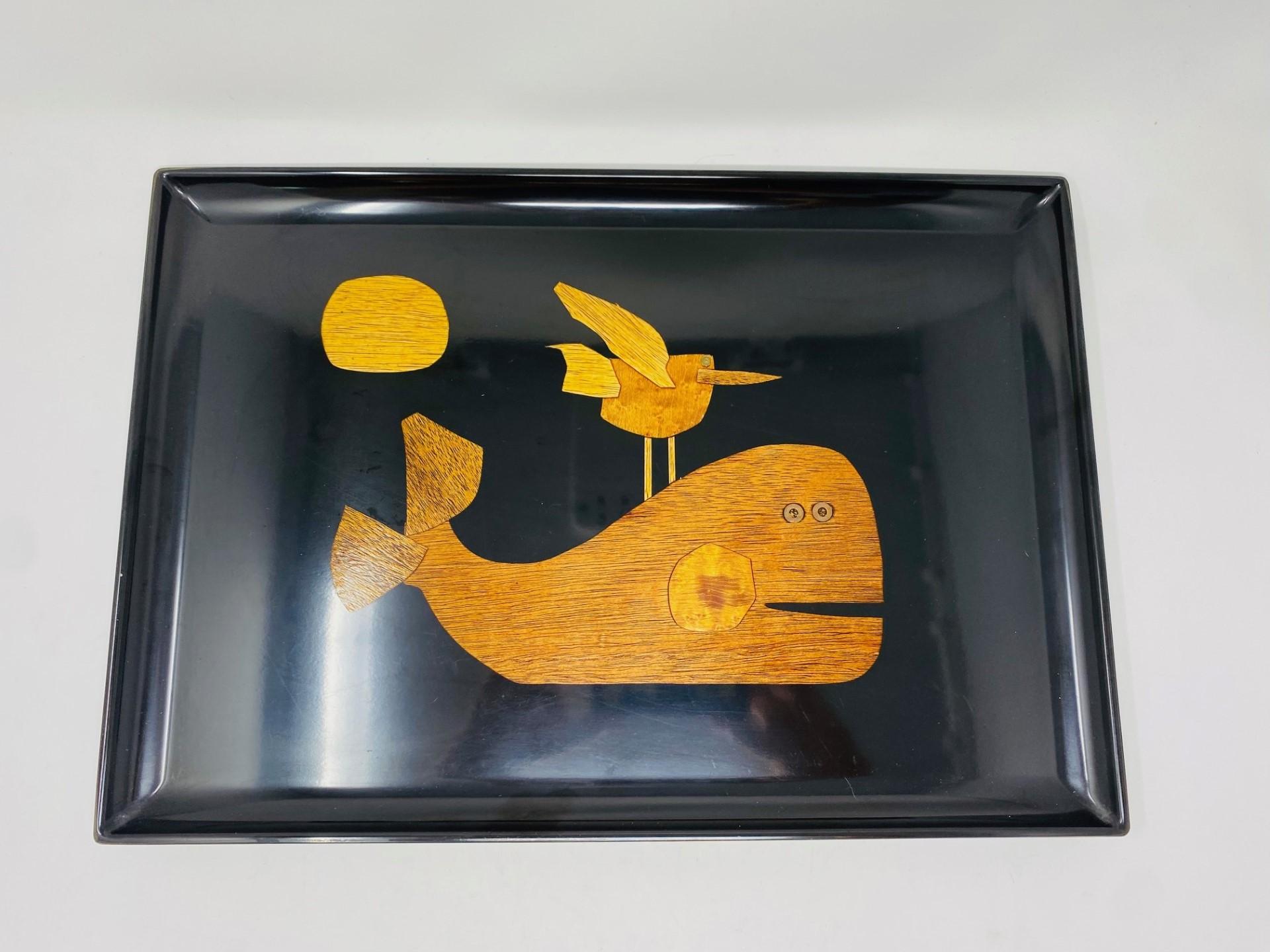 Mid 20th century serving tray by Couroc of Monterey, made from phenolic resin and inlaid with wood and brass depicting a whale with a bird perched on its back and the sun in the sky. Phenolic resin is resistant to damage from alcohol and water. 