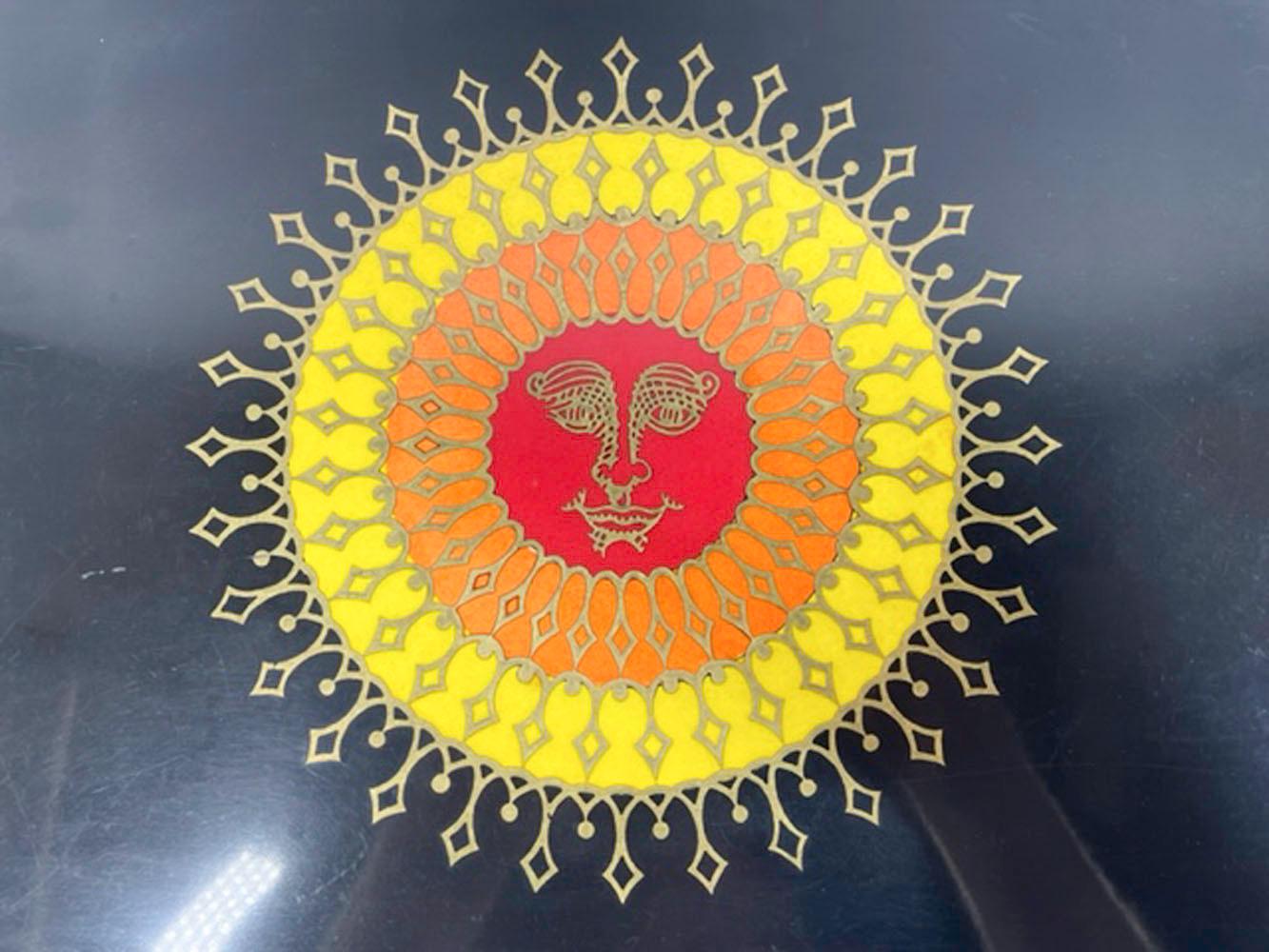 Vintage serving tray by Couroc of Monterey, made of phenolic resin inlaid with red, orange & yellow resin as well as brass, depicting a radiant sun with a face. 
Phenolic resin is resistant to damage from alcohol and hot water, making it ideal for
