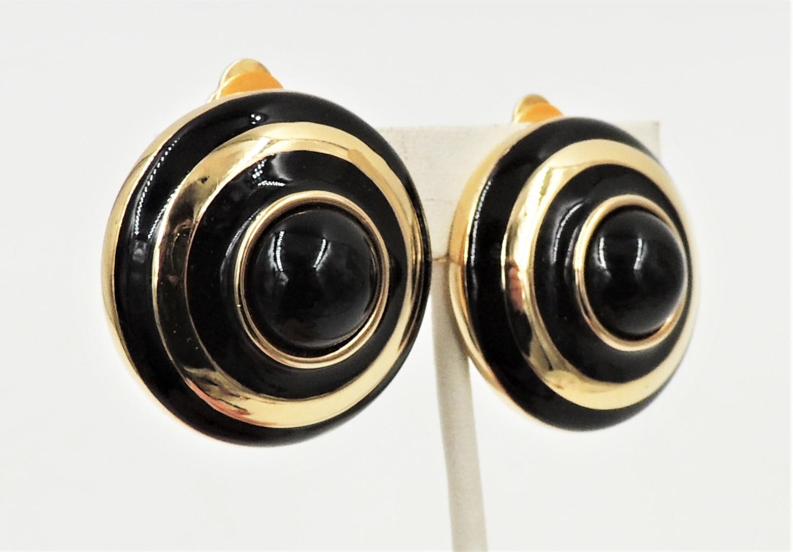 Circa 1980s gold plated cabochon faux-onyx rhinestone and black enamel clip back earrings. Marked with the Courrèges symbol. Measure: 1.38 inches across. Excellent condition.

Courreges is a French haute couture fashion house known for its modernism