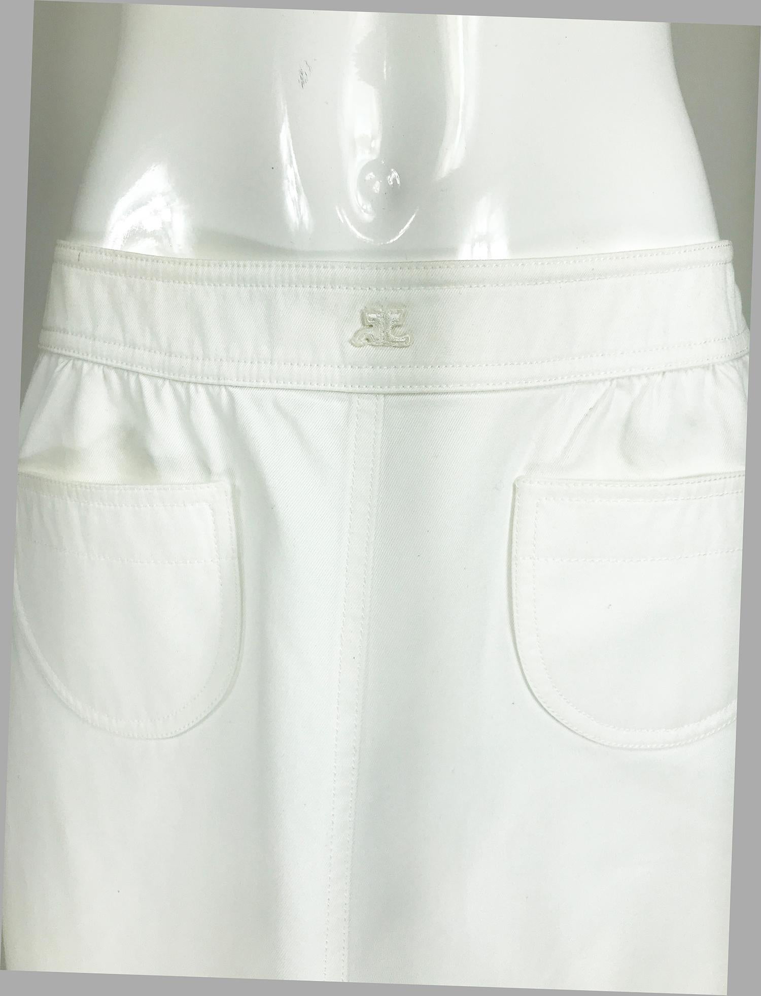 Vintage Courreges white cotton twill, pocket front skirt. Side zip skirt, has a contour shape waist band, with Courreges logo at the center front and closes with a white snap at the side. The skirt is lightly gathered below the waist band, two open