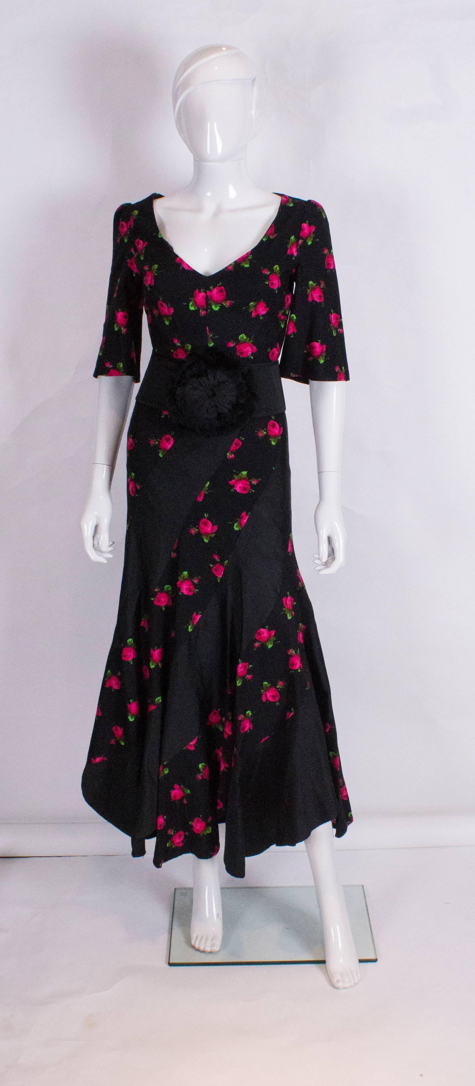 A super evening gown with spiral detail. This v neck dress in panels of black and black and pink panels in a spiral design.The dress is fully lined with an internal and external zip, and has elbow length sleeves and a scalloped hemline.