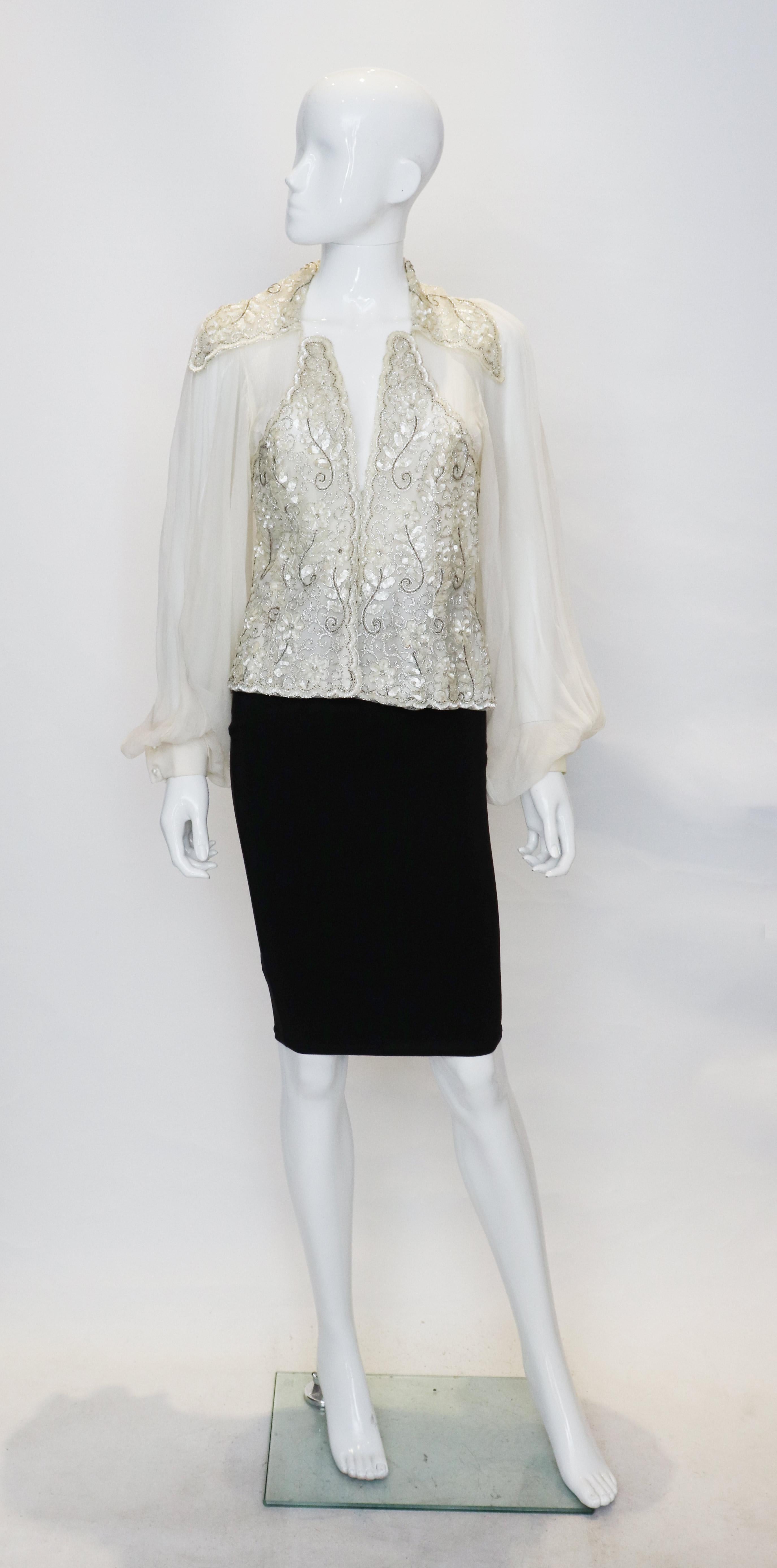 A superb vintage evening top in silk chiffon with wonderful sequin and bead detail on the front and back. The top has a v necklline, two button cuffs , hook and eye opening at the front, and pleats at the back yoke.