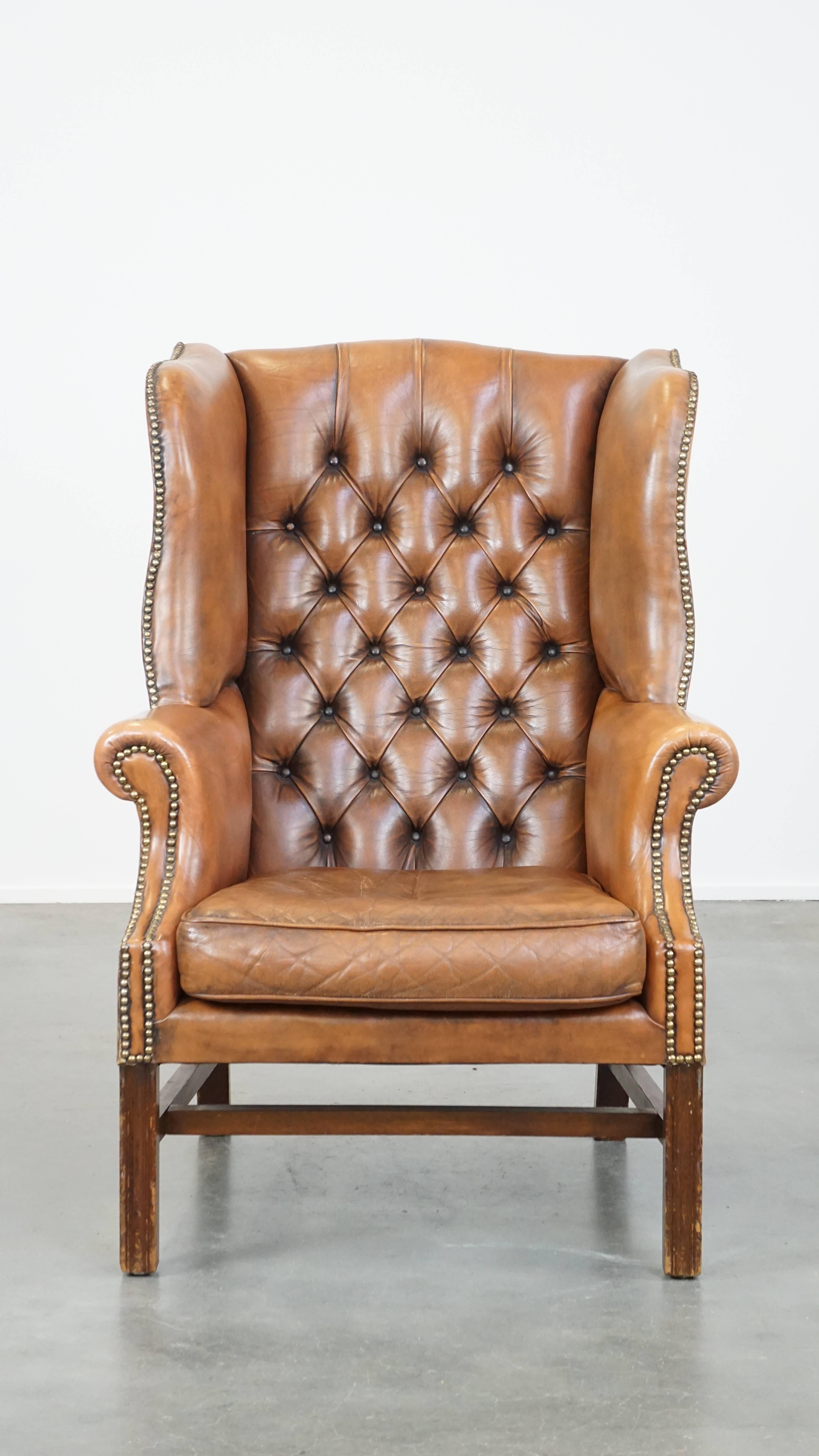 Luxury, character, and style; you can describe this leather English Chesterfield wingback chair with these three words. It has a light cognac color and a distinctive appearance. Due to its loose seat cushion and slim backrest, it is not a chair for
