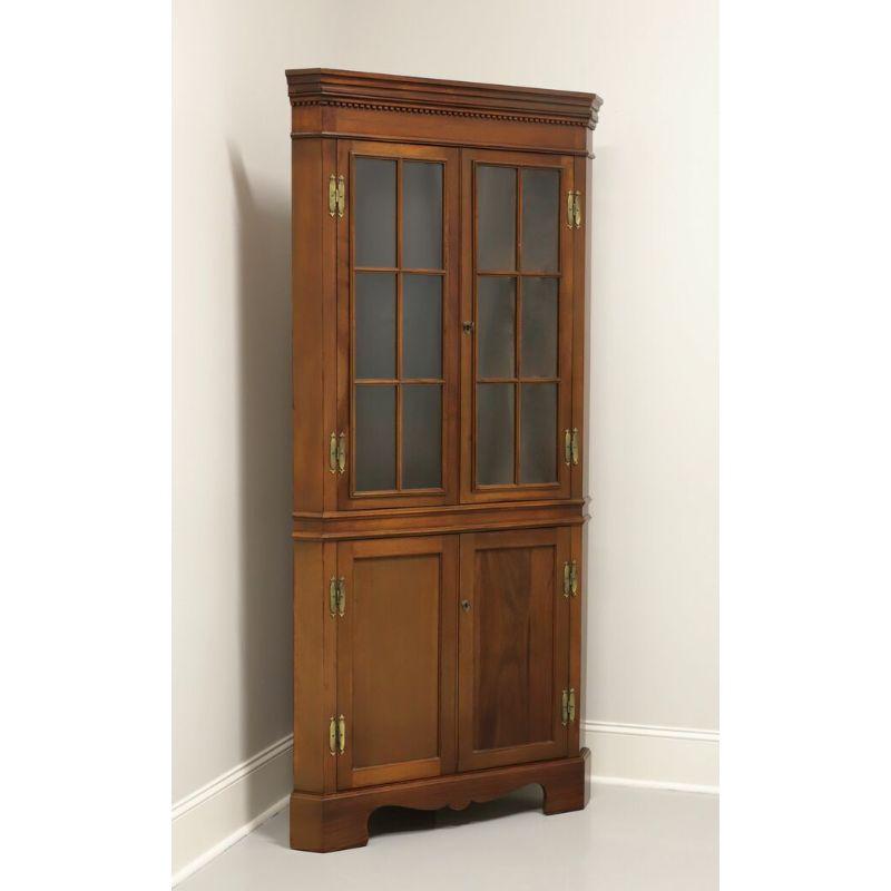 A Chippendale style corner cupboard by Craftique. Mahogany with crown & dentil molding, bracket feet and brass hardware. Upper cabinet features two fixed plate-grooved wooden shelves behind double doors, each with six panes of glass. Lower cabinet