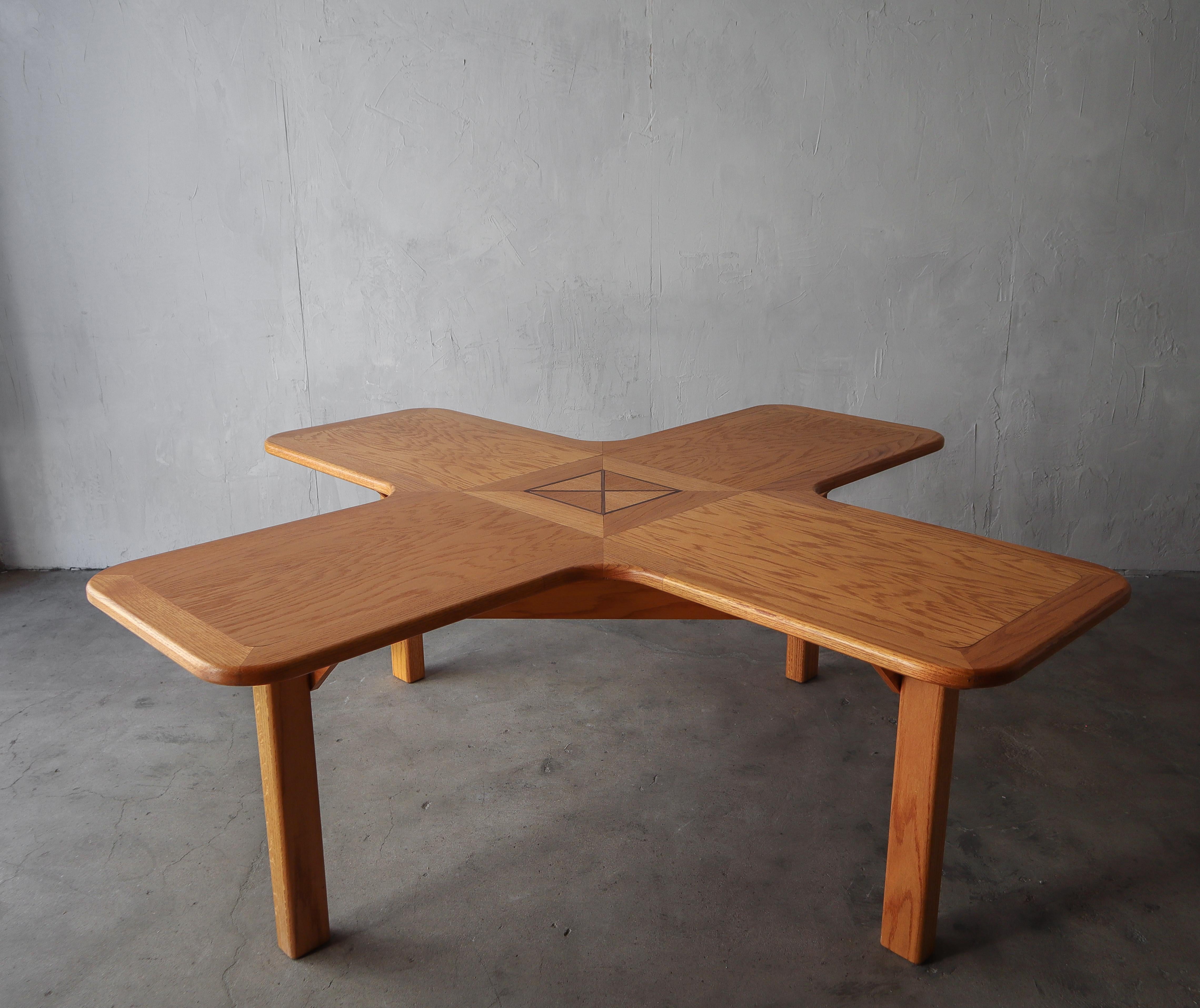 Ein einzigartiger Tisch, der auf vielfältige Weise genutzt werden kann. Gefertigt aus massiver Eiche in Form eines X oder eines Pluszeichens, je nachdem, wie man es betrachtet, mit einem einzigartigen Intarsienmuster in der Mitte. Dieser Tisch