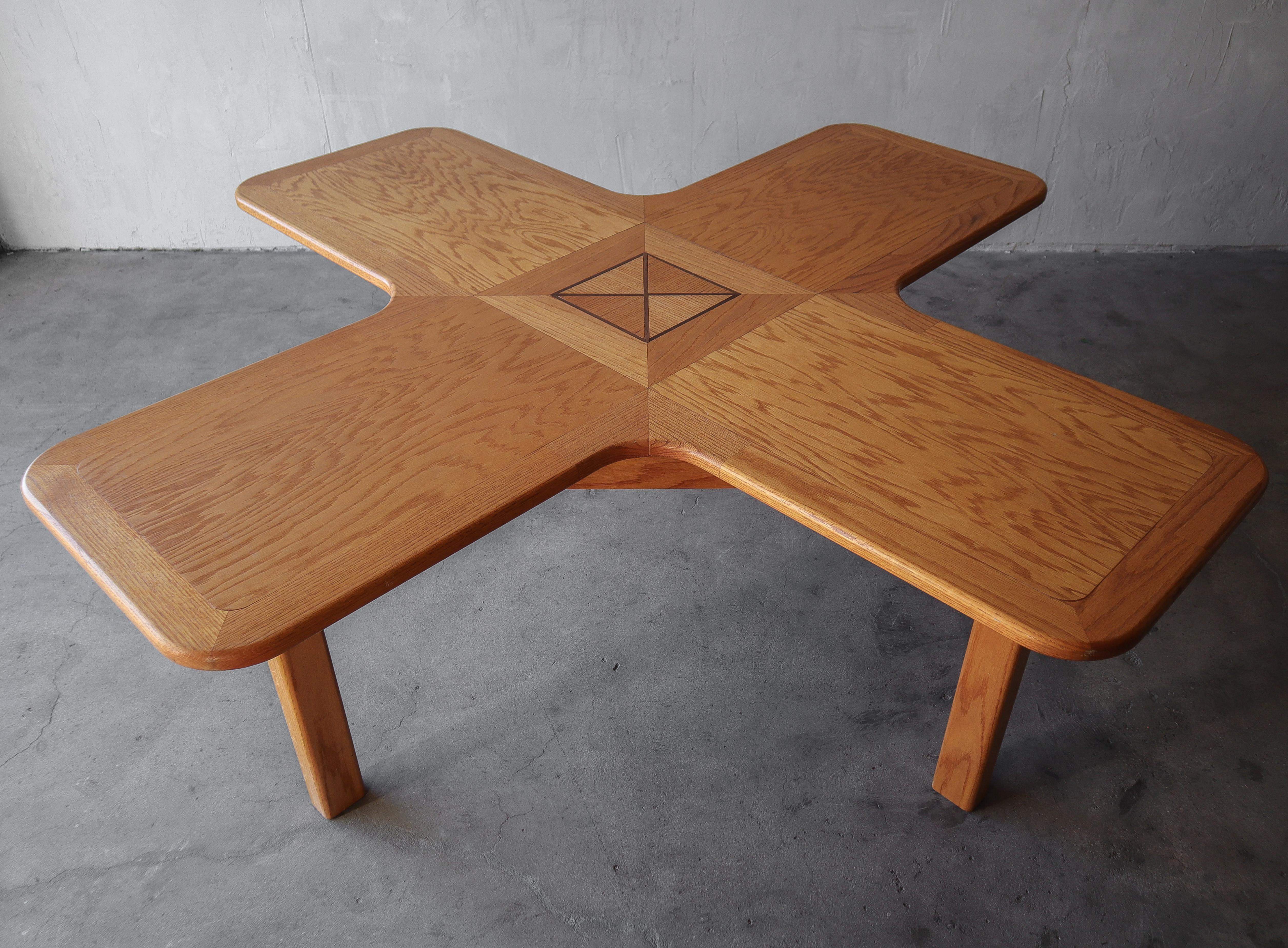 Un tavolo unico che può essere utilizzato in molti modi. Realizzato in legno massiccio di quercia a forma di X o di segno più, a seconda di come lo vedi, con un esclusivo disegno intarsiato al centro. Questo tavolo sarebbe un fantastico centro