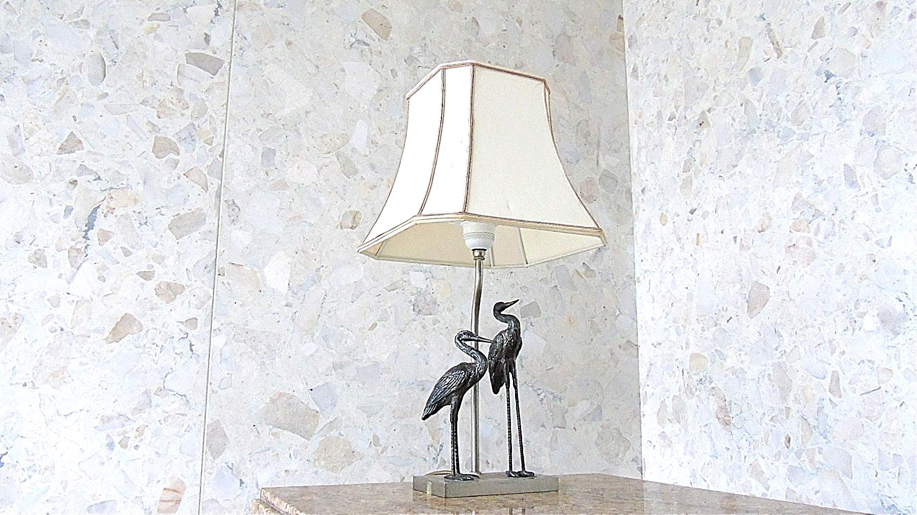 Beautiful sculptural table lamp depicting two crane birds in the style of Maison Baguès.

The lamp is a late 1950s-early 1960s example and comes with a period shade.

Beautiful patina.

Tested and ready to use with a regular E27 light