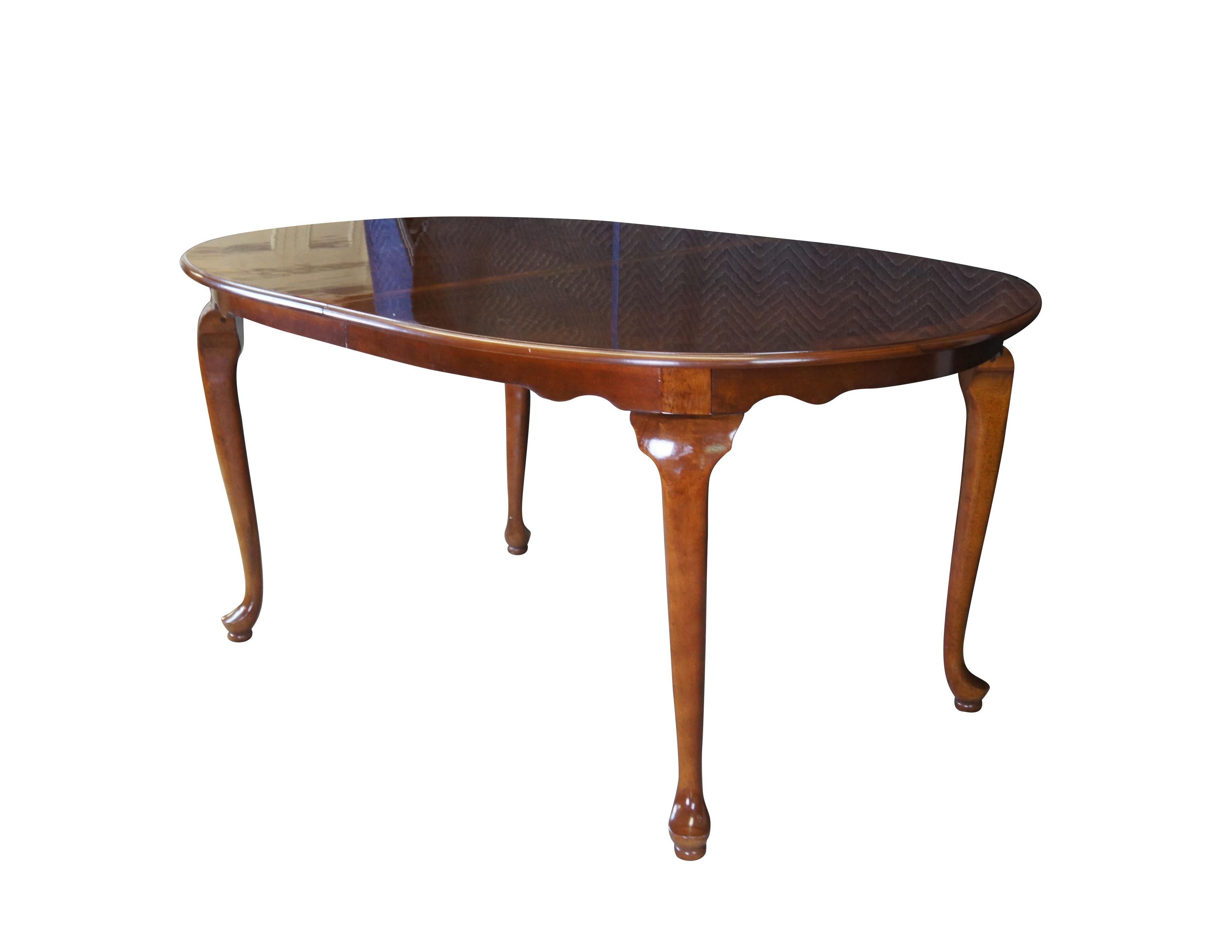 A lovely dining table by Cresent Manufacturing Company, circa 1970s. Features an oval Queen Anne form made from cherry with banded edge around the top. Includes two leaves for extension up to 93
