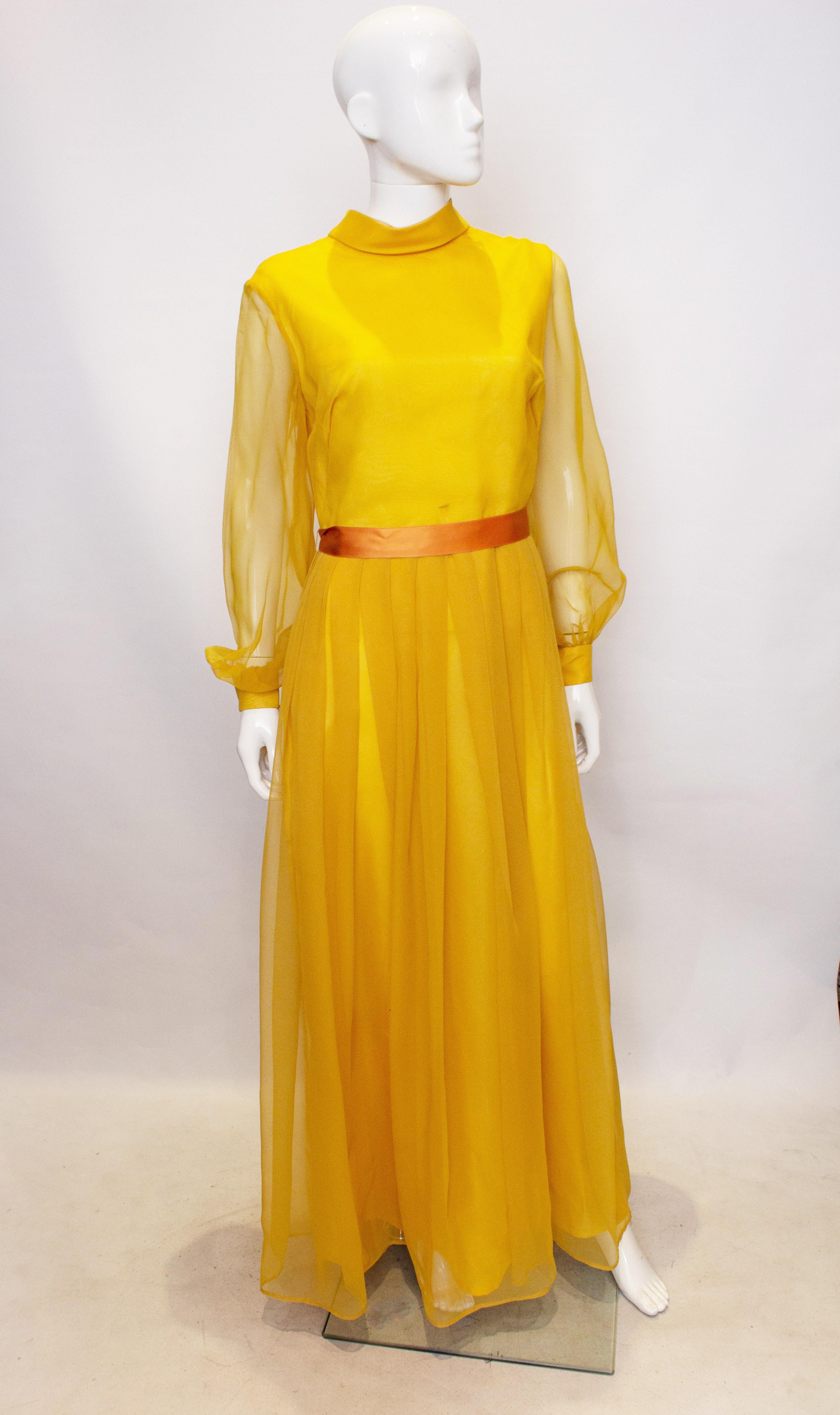 A stunning vintage evening gown by Cresta. The dress has a stand up collar, sheer sleaves , a ribbon belt, and central back zip.