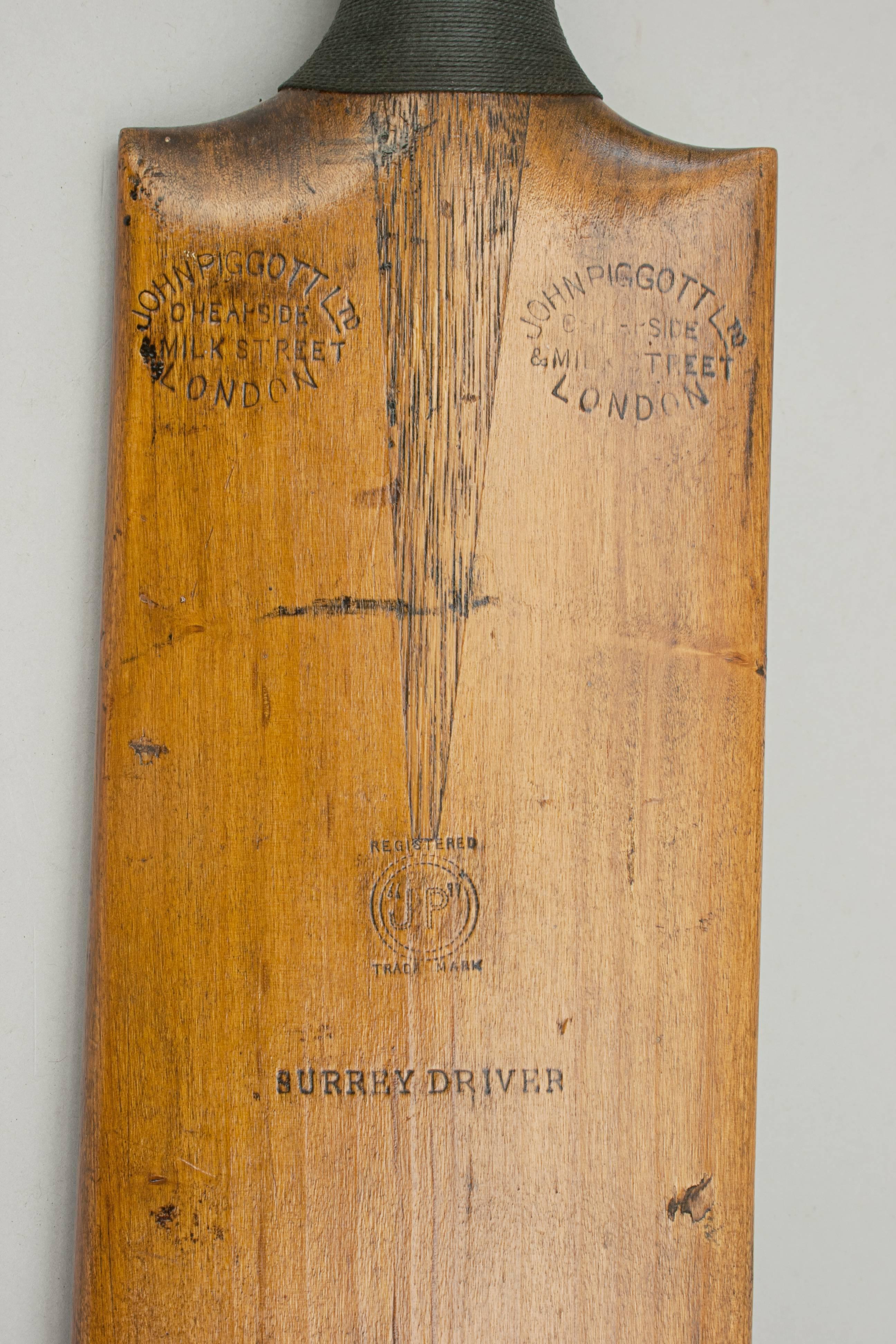 Surrey Driver cricket bat.
A thick handled willow cricket bat retailed by John Piggott Ltd., London. The bat has nice round shoulders, corded grip with the bat embossed 'John Piggott Ltd., Cheapside, Milk Street, London' on both shoulders, 'Surrey