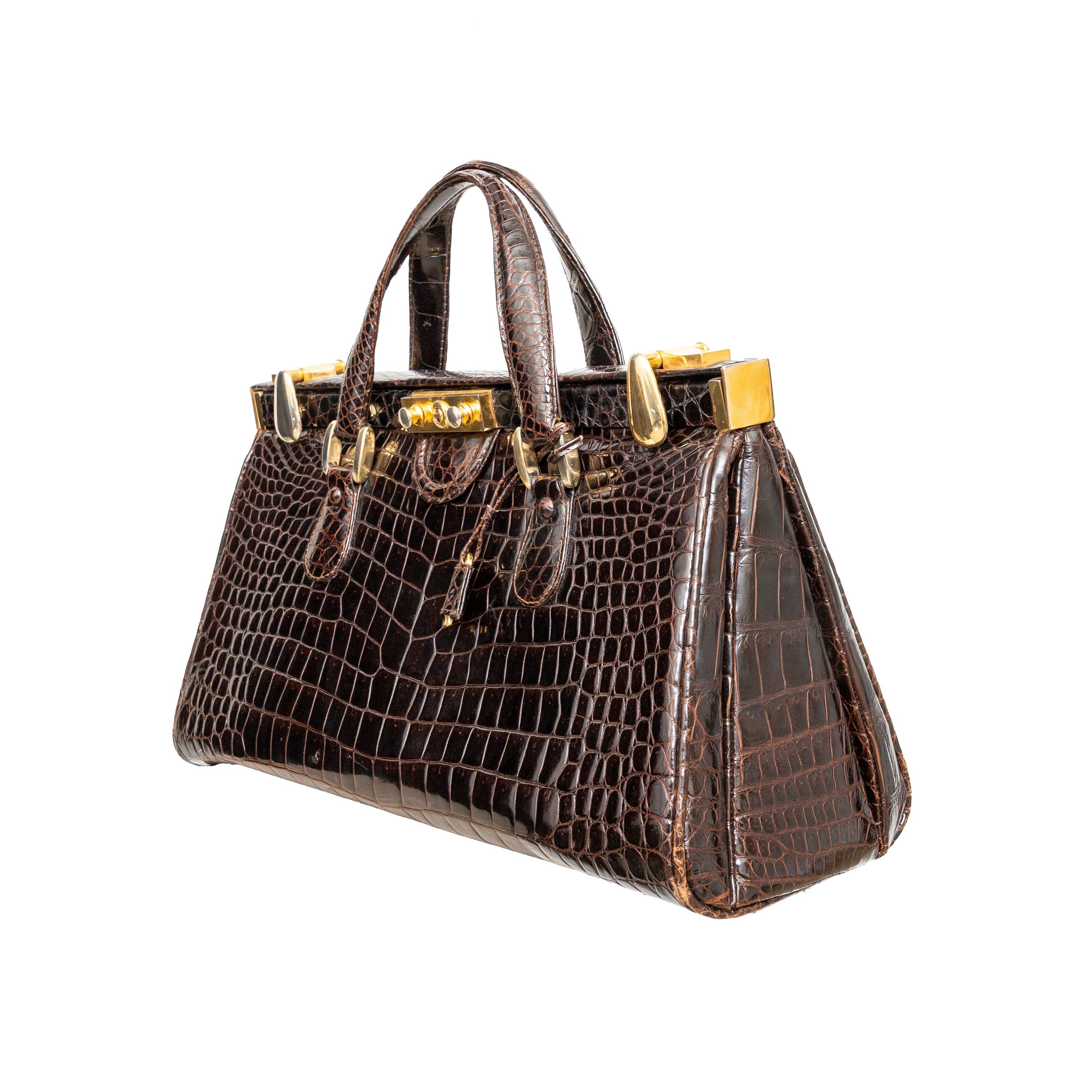Questa borsa in pelle di coccodrillo vintage degli anni '90 emana eleganza grazie al suo ricco colore marrone mogano e ai robusti manici superiori. L'hardware dorato aggiunge un tocco di lusso, mentre la chiusura a moschettone e il foro per le