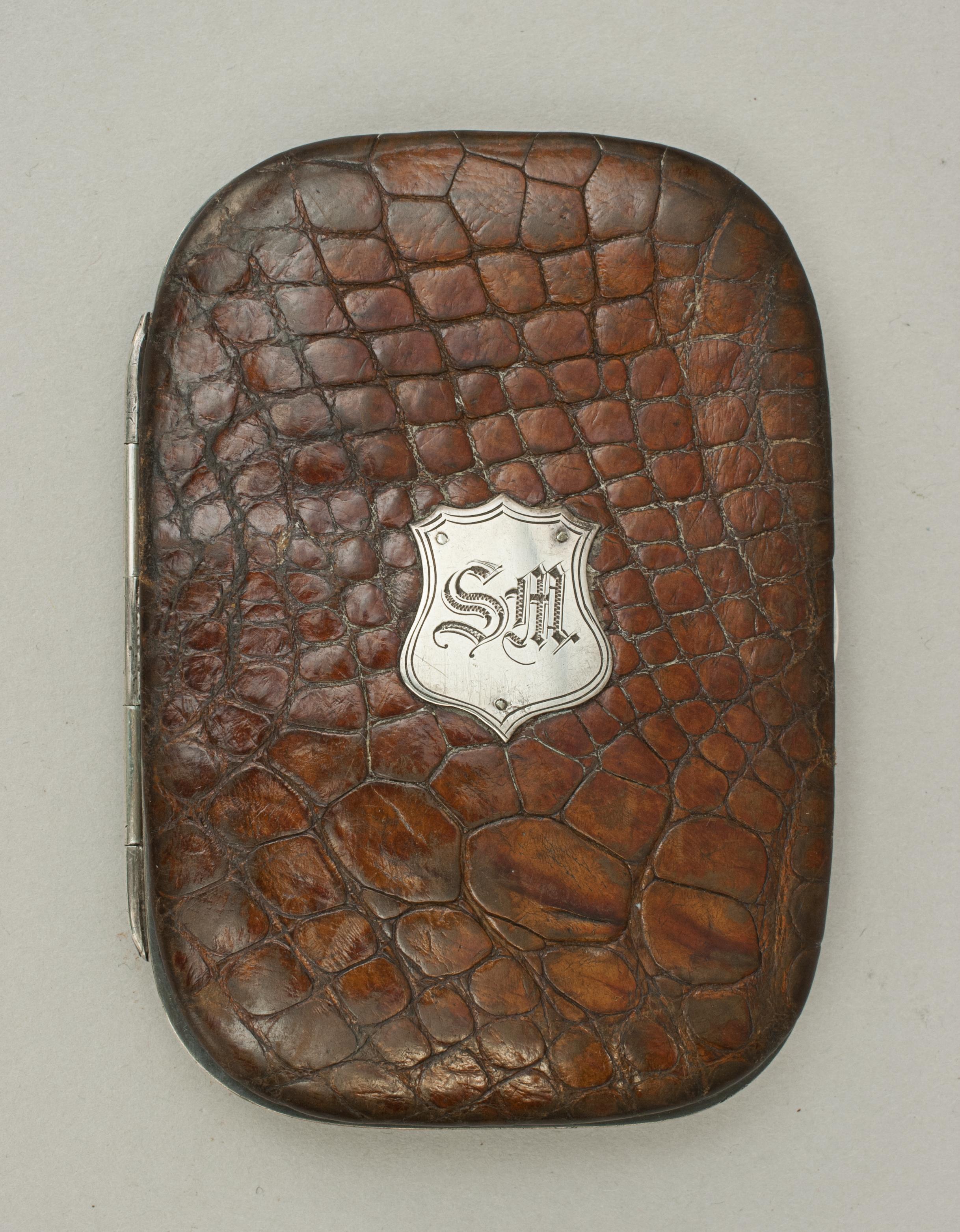 Leather crocodile calling card wallet, postage stamp case.
An unusual crocodile leather postage stamp or calling card case with silvered frame and central catch. The front with silvered shield with the initials 'SM'. Interior very nice with leather