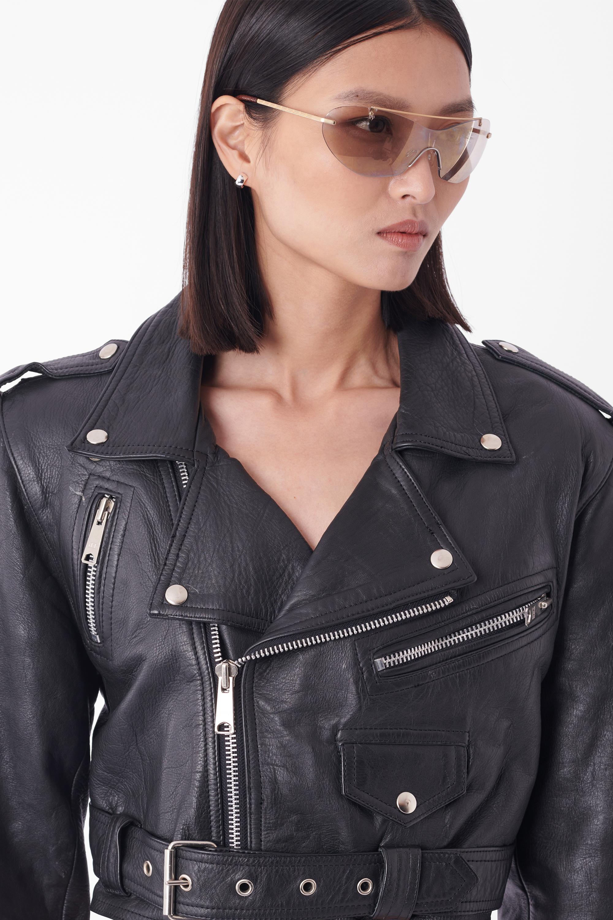 We are excited to present this Vintage cropped leather biker jacket. Features bulky silhouette in a semi-cropped finish, silver hardware zips with three front pockets and waistband belt. In good vintage condition, some minor wear to the leather.