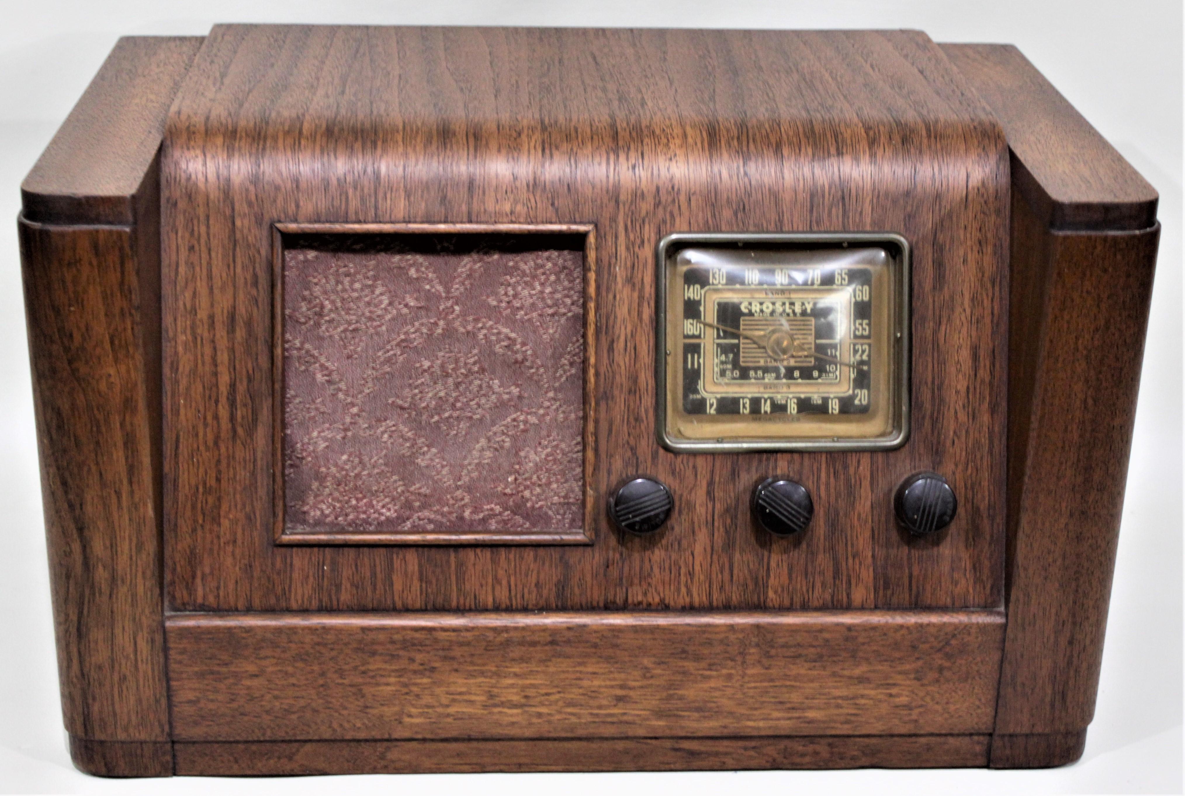 This vintage Crosley 3-band AM/shortwave radio was made in their Cincinnati factory in circa 1940 in the Mid-Century style. This radio is done in a walnut case with bakelite knobs and a chocolate brown and brass dial face and brass double needle