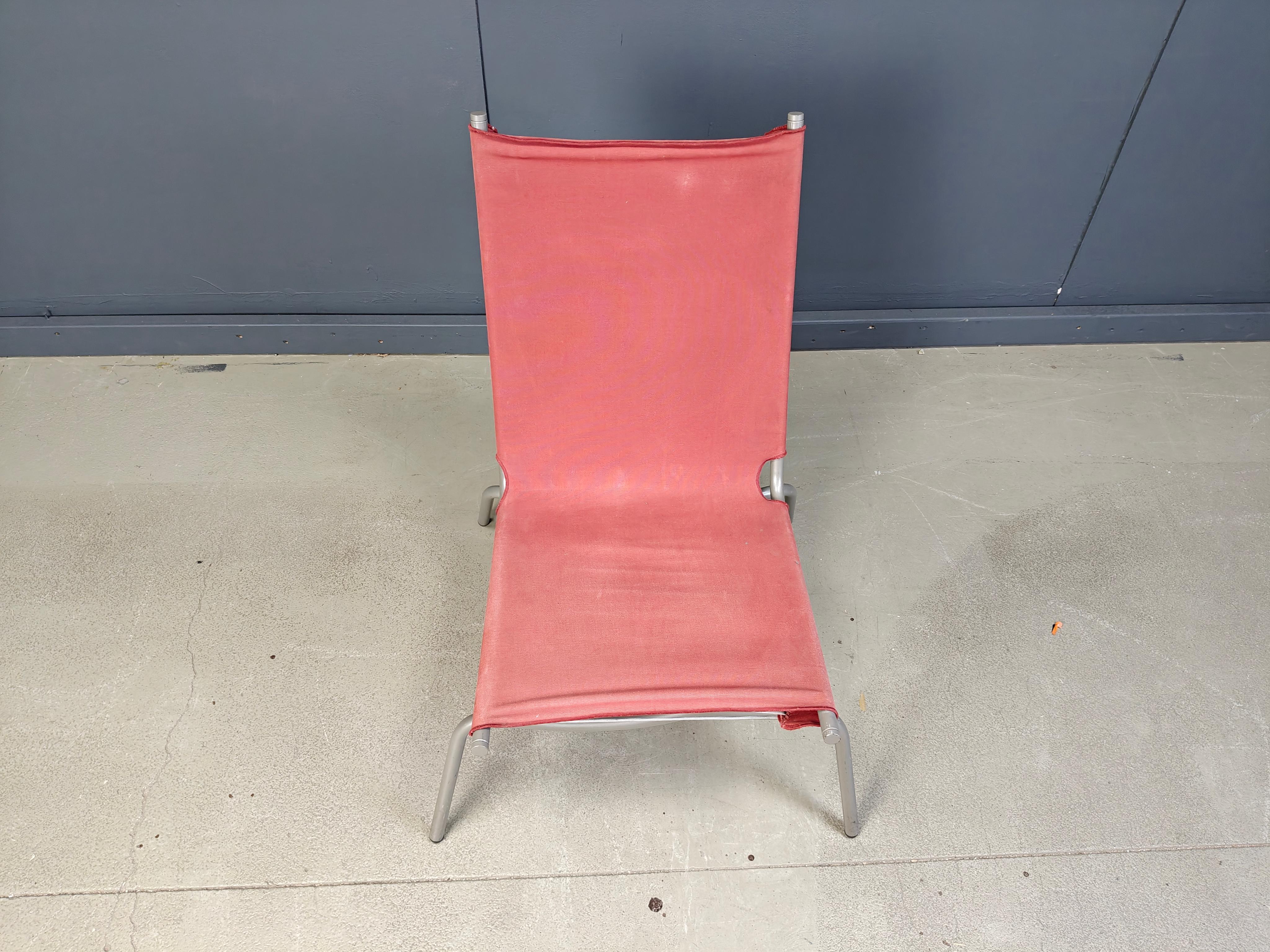 Silla de salón de finales de los 90 diseñada por Fabiaan Van Severen que consiste en un armazón de metal tubular gris de patas cruzadas con un tapizado de lona roja y cuerda.

Hermosa pieza de diseño que encajará en la mayoría de los interiores