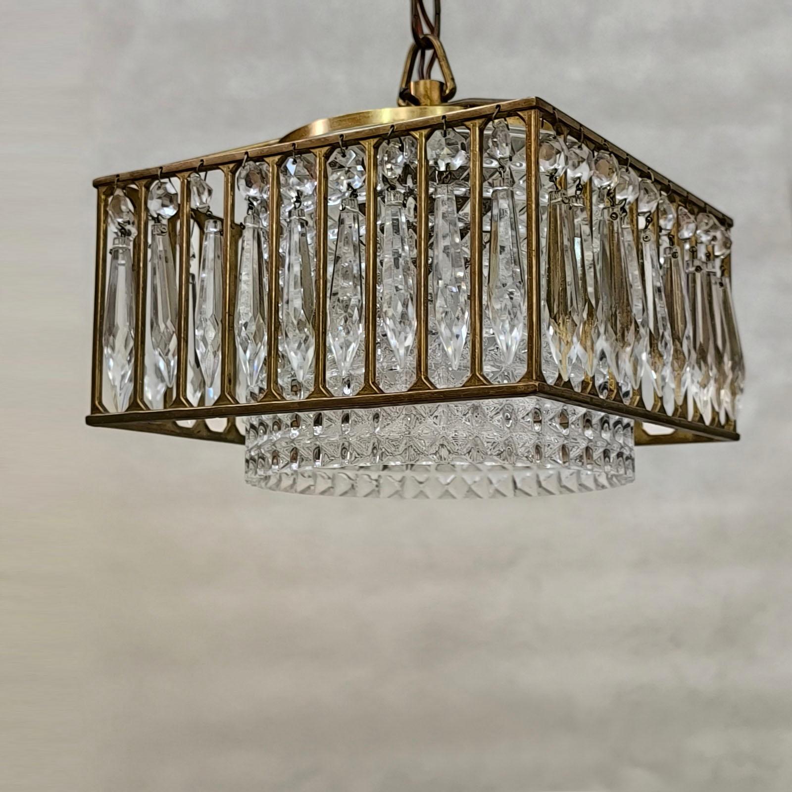 Plafoniera d'epoca in ottone e vetro di cristallo, 1970-1980 circa. 
Con una costruzione geometrica, questo elegante ciondolo è strutturato come un'intersezione di volumi, calcolata per offrire la luce e l'aspetto migliori in un apparecchio di