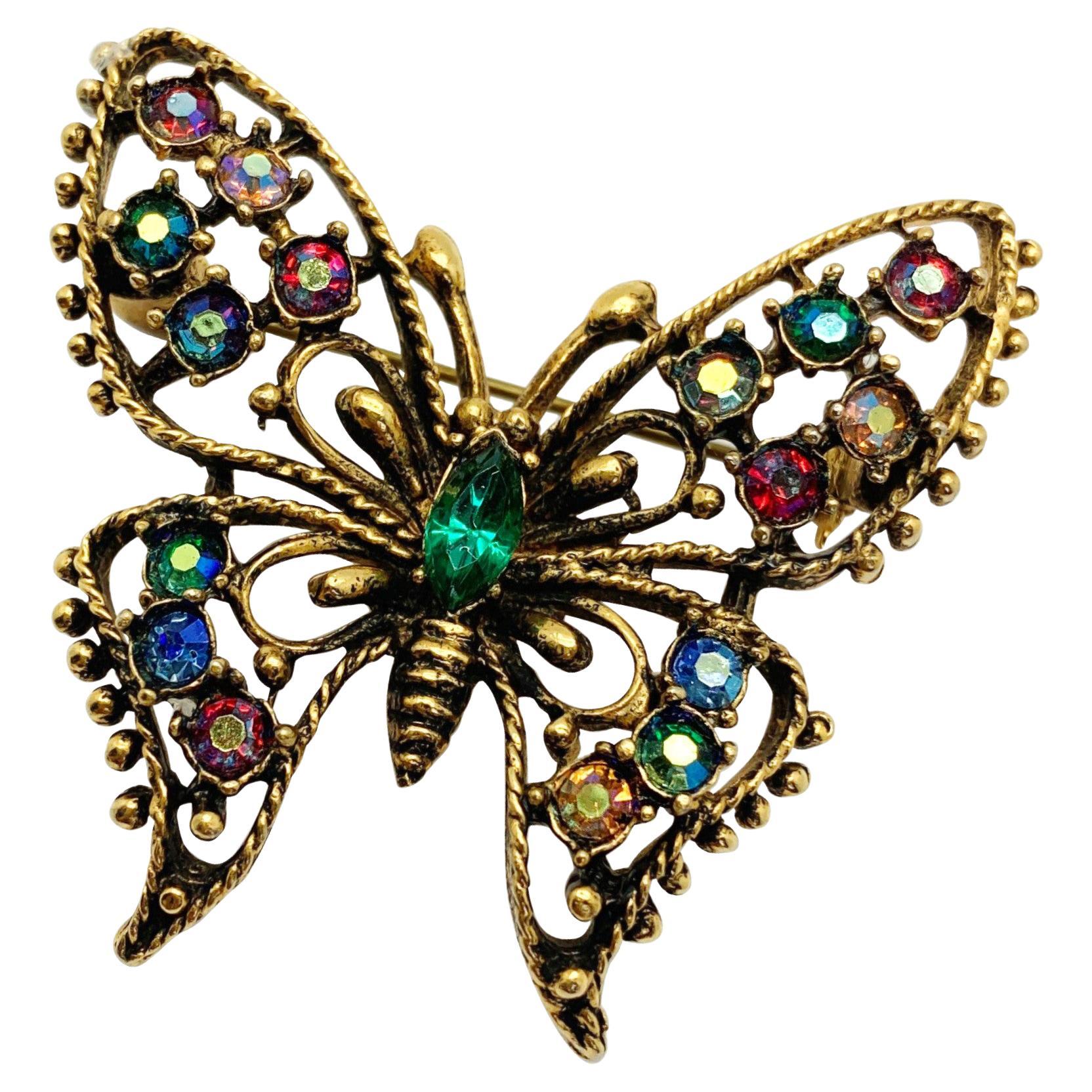 A gorgeous vintage crystal butterfly brooch. Featuring a wonderful rainbow of aurora borealis glass crystal stones in an open antiqued gold framework, depicting a wings outstretched butterfly. 
Vintage Condition: Very good without damage or