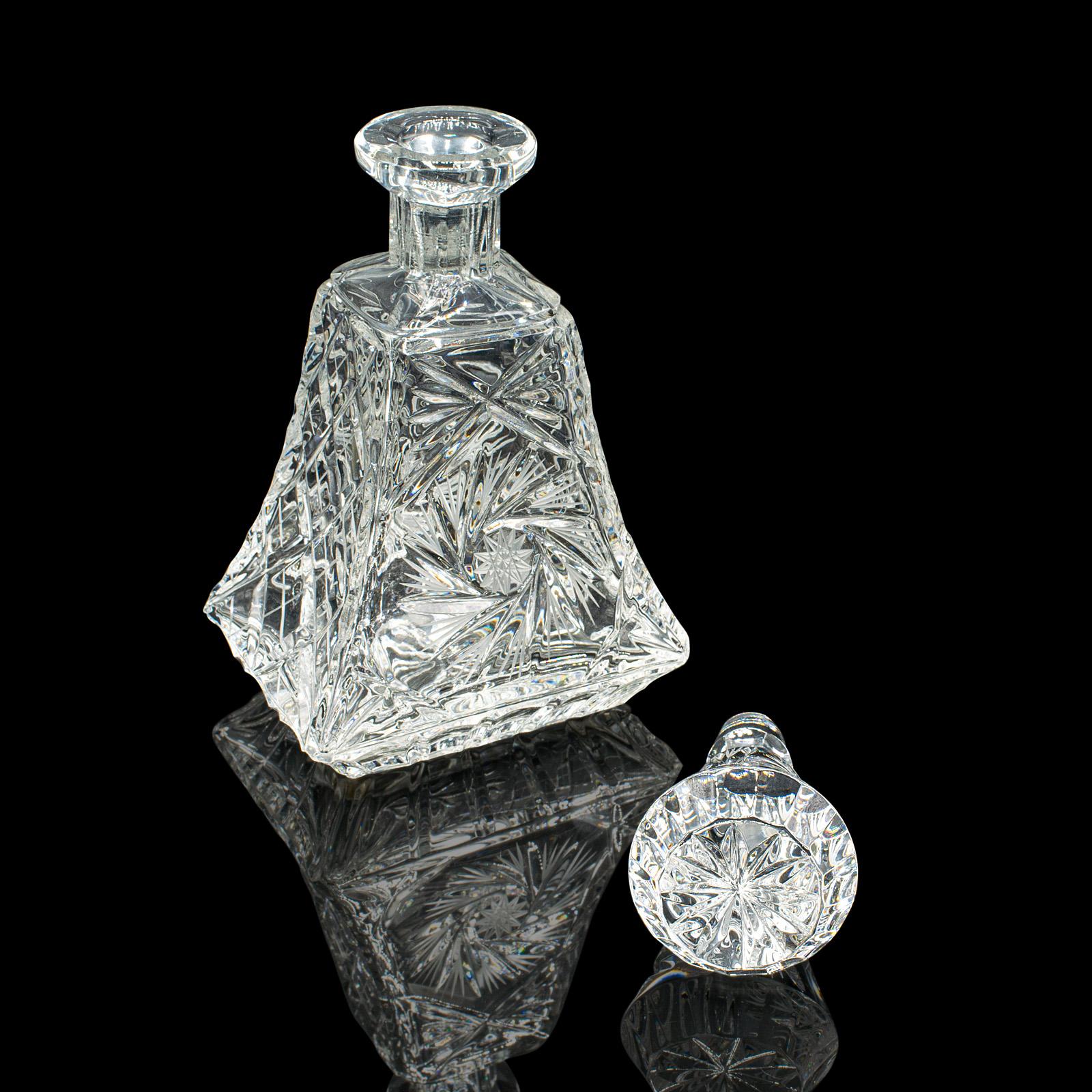 This is a distinguished mid 20th century brandy decanter, showcasing exquisite English cut glass craftsmanship, circa 1960. This vintage decorative spirit vessel boasts a distinctive form with intricate detailing, perfect for refined home bars and