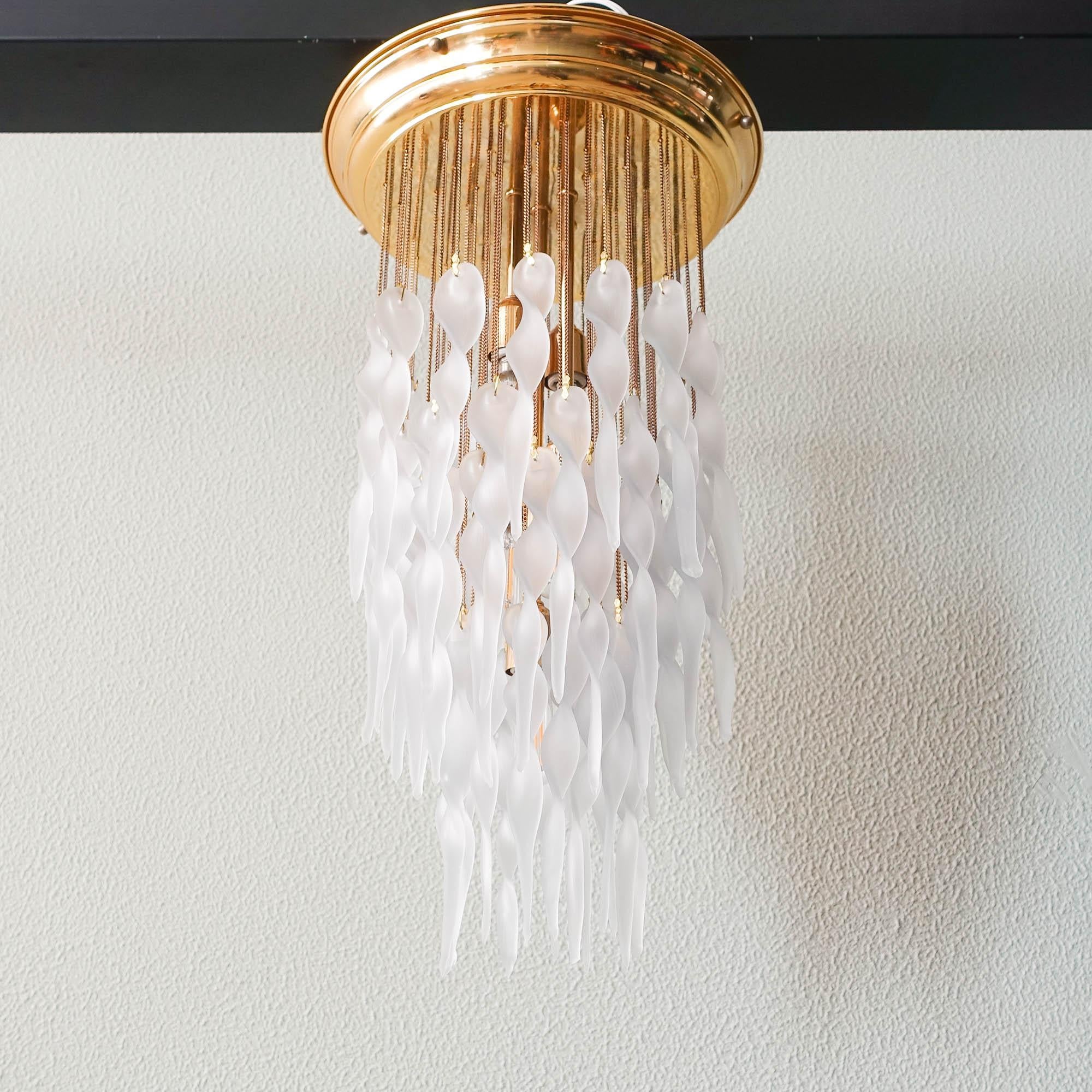 This pendant lamp was designed by Paolo Venini for Venini during the 1970s, in Italy. It features a brass plate were dozens of frosted glass drops fall creating a layering effect with three tiers. The fixture requires 5 x E14 bulbs. In original and