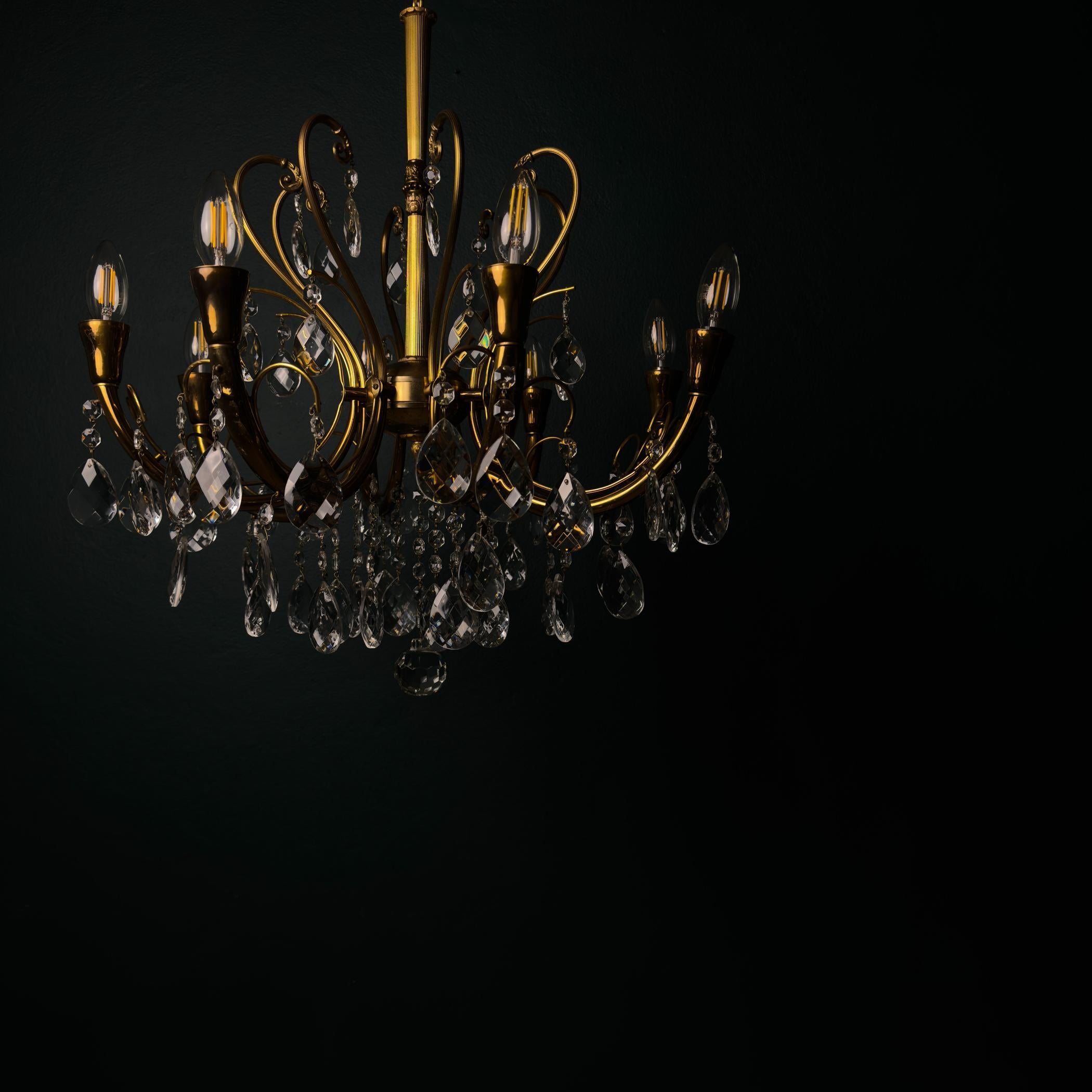 Un elegante lampadario in bronzo dorato e cristallo realizzato in Italia negli anni Cinquanta.
Questo lampadario classico ha una forma snella e sinuosa in bronzo dorato. Le pendole sfaccettate a goccia e i fiocchi di cristallo disperdono