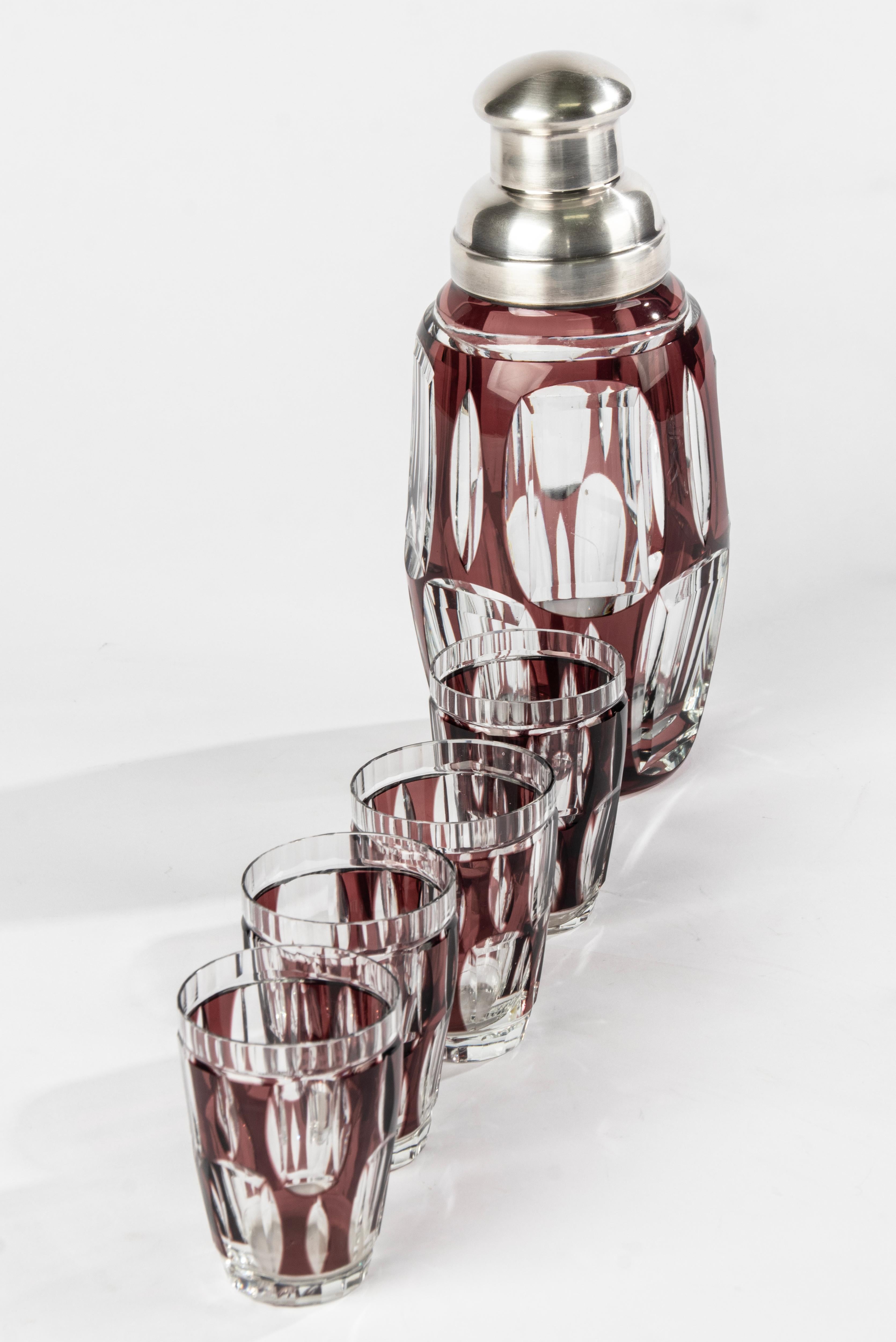 A great crystal cocktail shaker with silver plated top and 5 matching liquor glasses. 
The silver plated part is marked Wiskemann. There is nog signature found on the crystal, but the beautiful mauve colour and the quality of the crystal indicates a