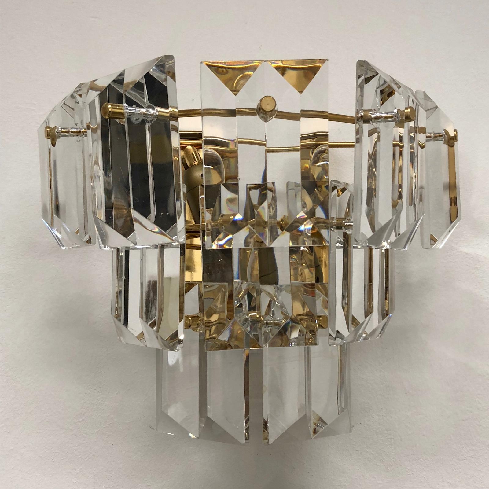 Elegant wall light with crystal glass panels. It's made of gold-plated metal and glass. This fixture requires two European E14 candelabra bulbs, up to 40 watts each. A view little chips or flea-bits on the backside of the glass, also little bended