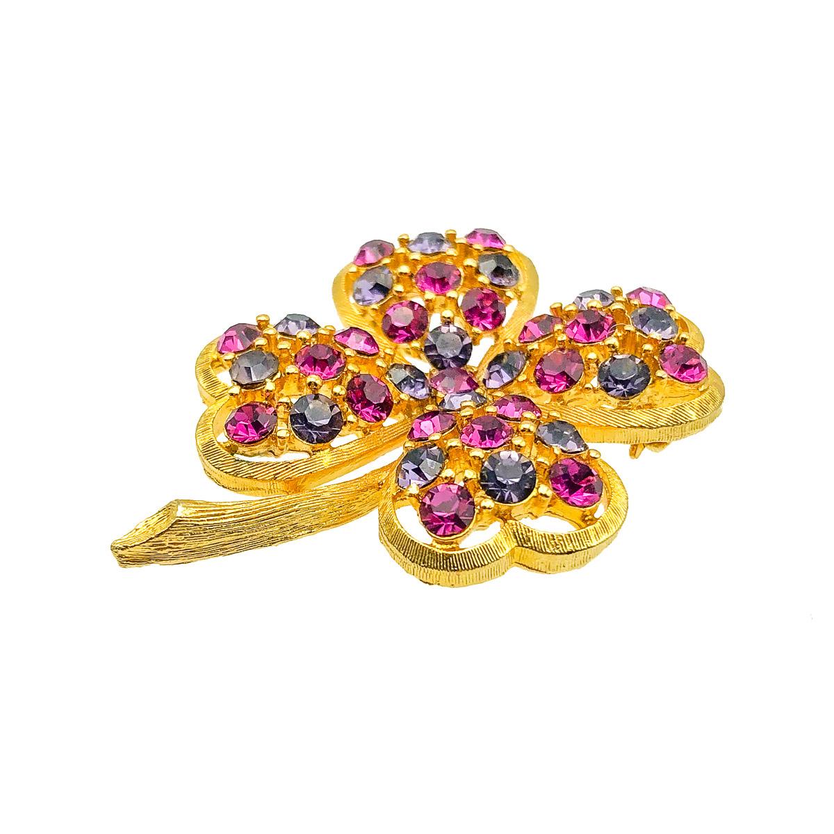 A very pretty Vintage Crystal Shamrock Brooch. The three leaves of a shamrock are said to stand for faith, hope and love. A fourth leaf is said to bring luck. Crafted in gold tone metal with pink and purple crystal stones. In very good vintage