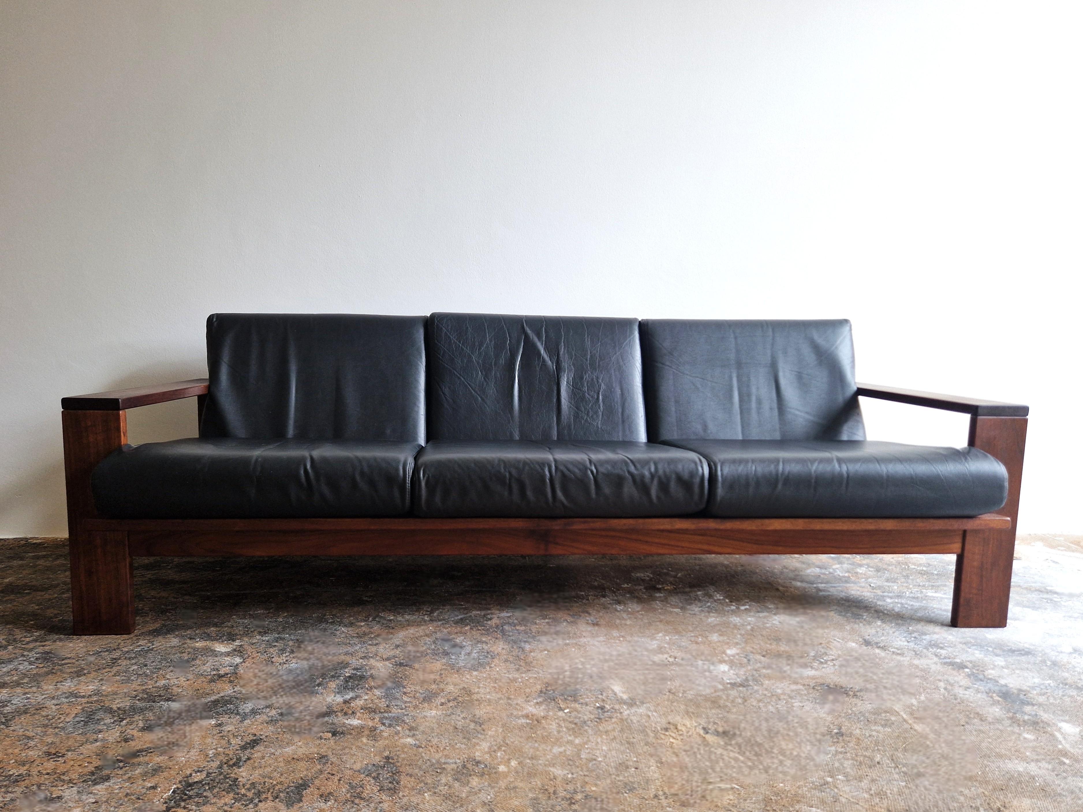 Ce superbe canapé 3 places vintage présente un design cubiste solide et de bonne facture. Fabriqué à partir d'un cadre en bois solide et de coussins confortables en similicuir. 
Nous avons obtenu ce canapé de la fille du premier propriétaire, qui