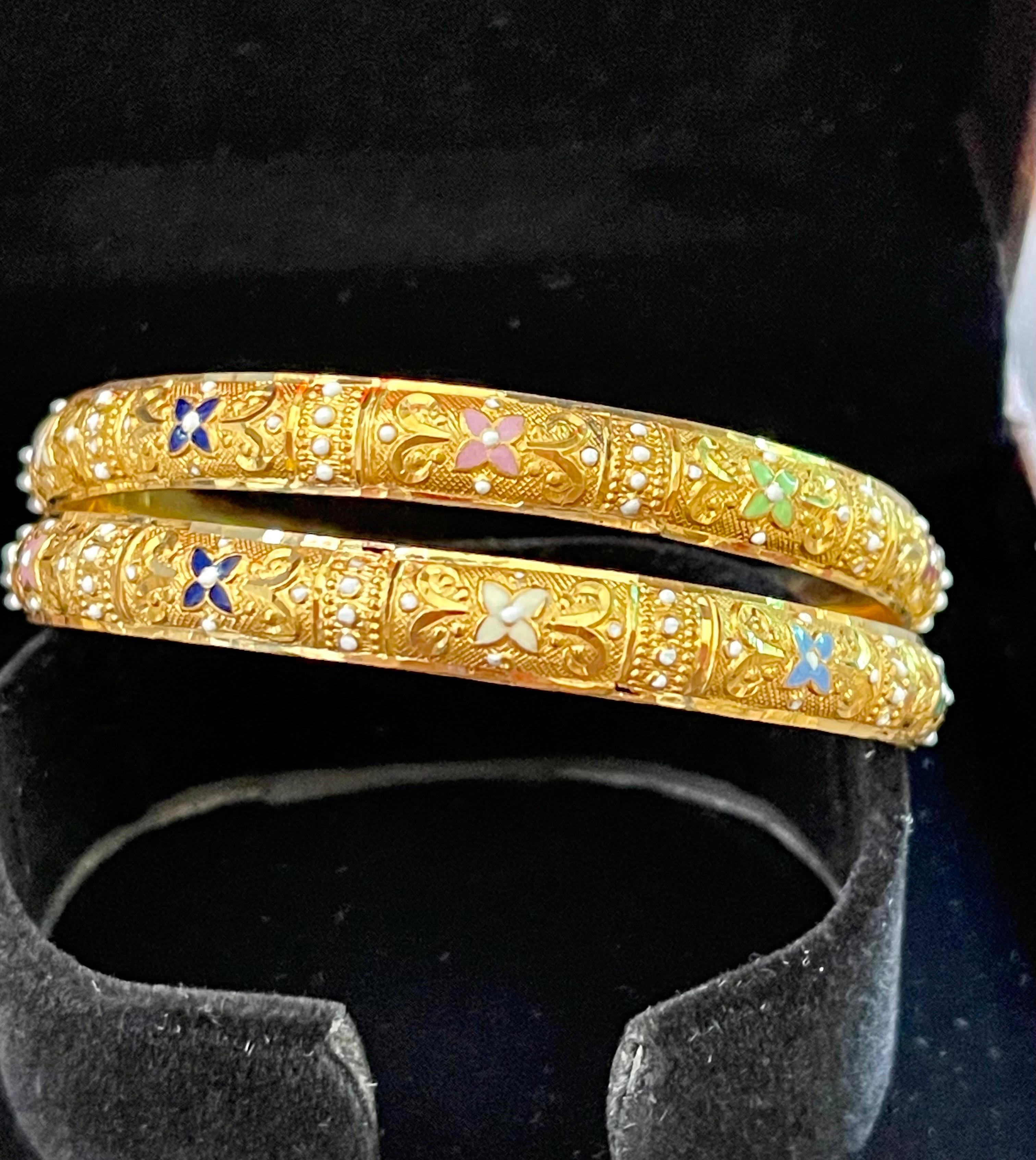 
A quality Pair of hand engraved bright twenty two karat (22K) yellow gold bangle bracelets with red and green enamel accents, finely crafted on the sub-continent of India. Slide on style measuring 2-1/4 inches in diameter . 
It will fit to a small