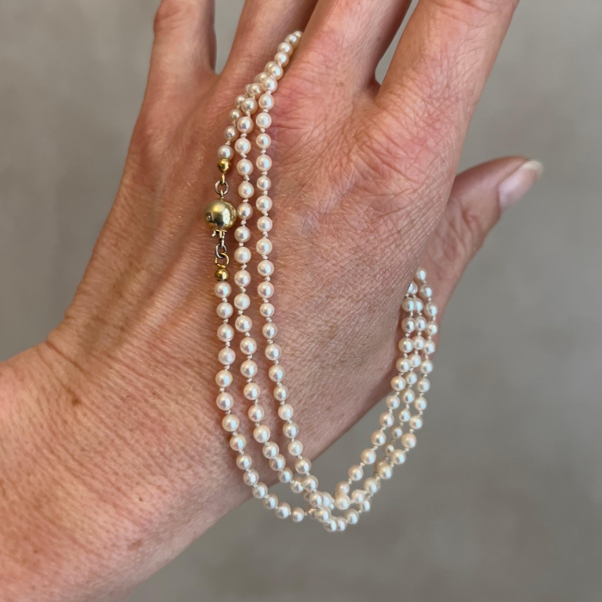 This vintage necklace is an elegant piece, featuring a delicate strand of small, round cultured pearls. Each pearl is lustrous with a soft sheen, showcasing the timeless beauty that pearls are known for. The pearls are uniformly sized, creating a