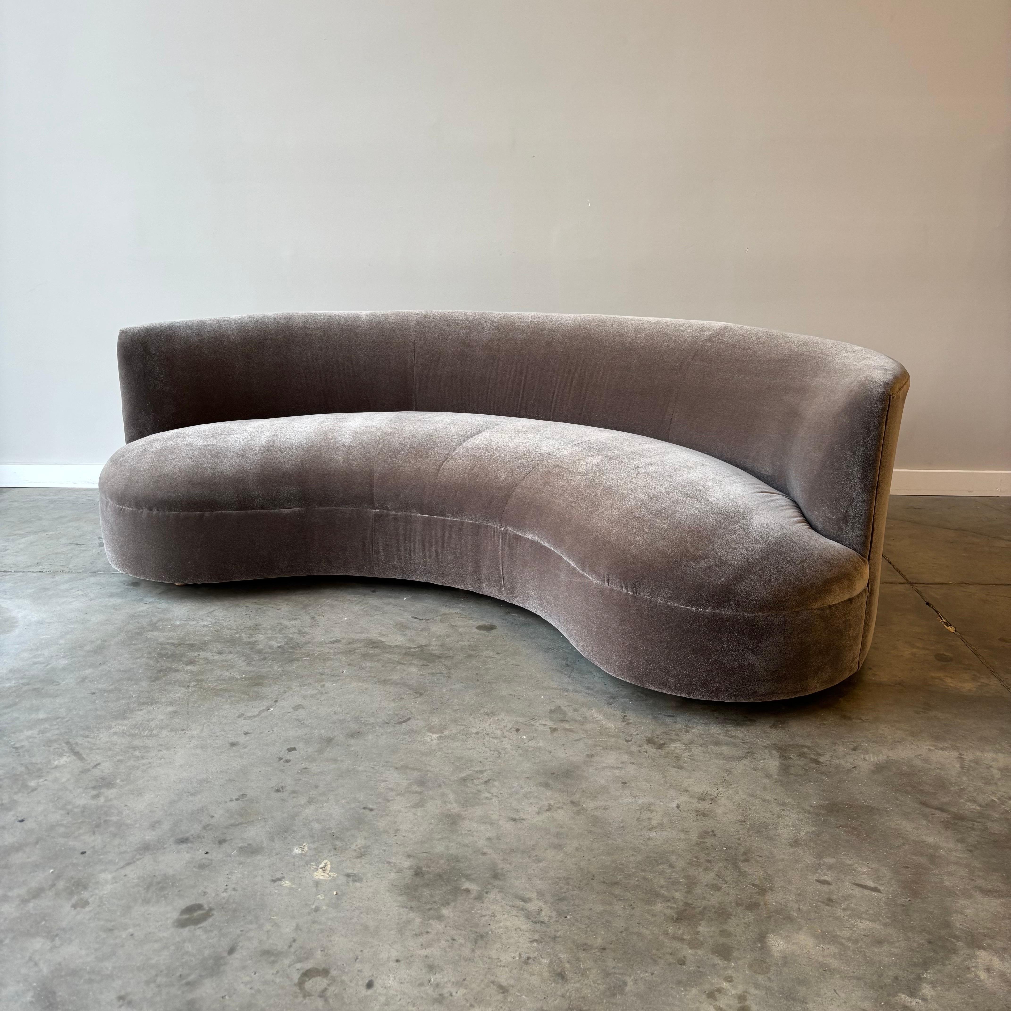 
La amplia silueta curvada define este sofá de estilo John Mascheroni, que muestra el arco dramático y las generosas proporciones características de los asientos escultóricos de los años setenta. La curva continua crea una forma envolvente que ancla