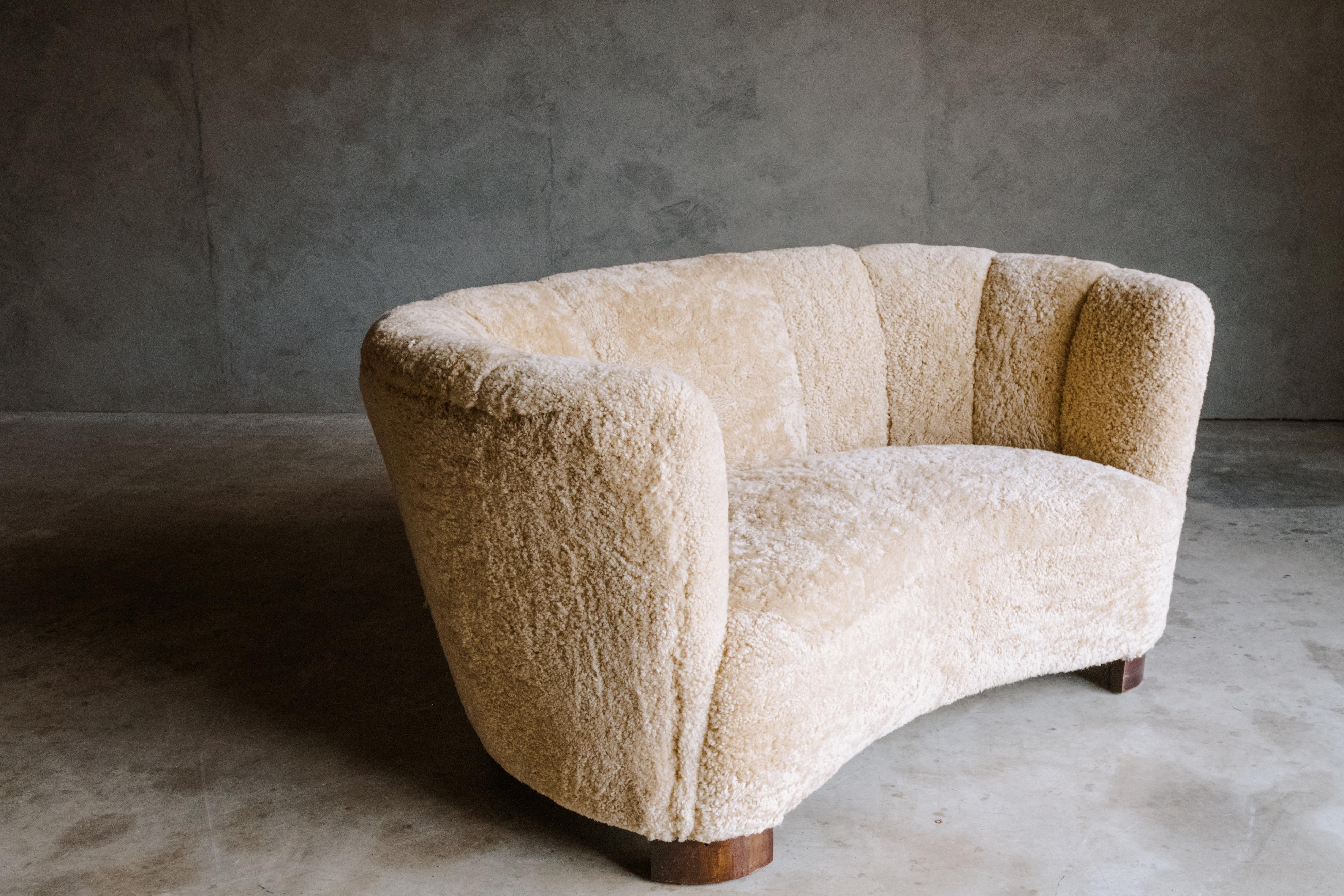 Vintage curved two seater sofa in sheepskin, From Denmark, Circa 1950. Danish cabinetmaker designed. Later professionally upholstered in Denmark. Very soft shearling in excellent condition.