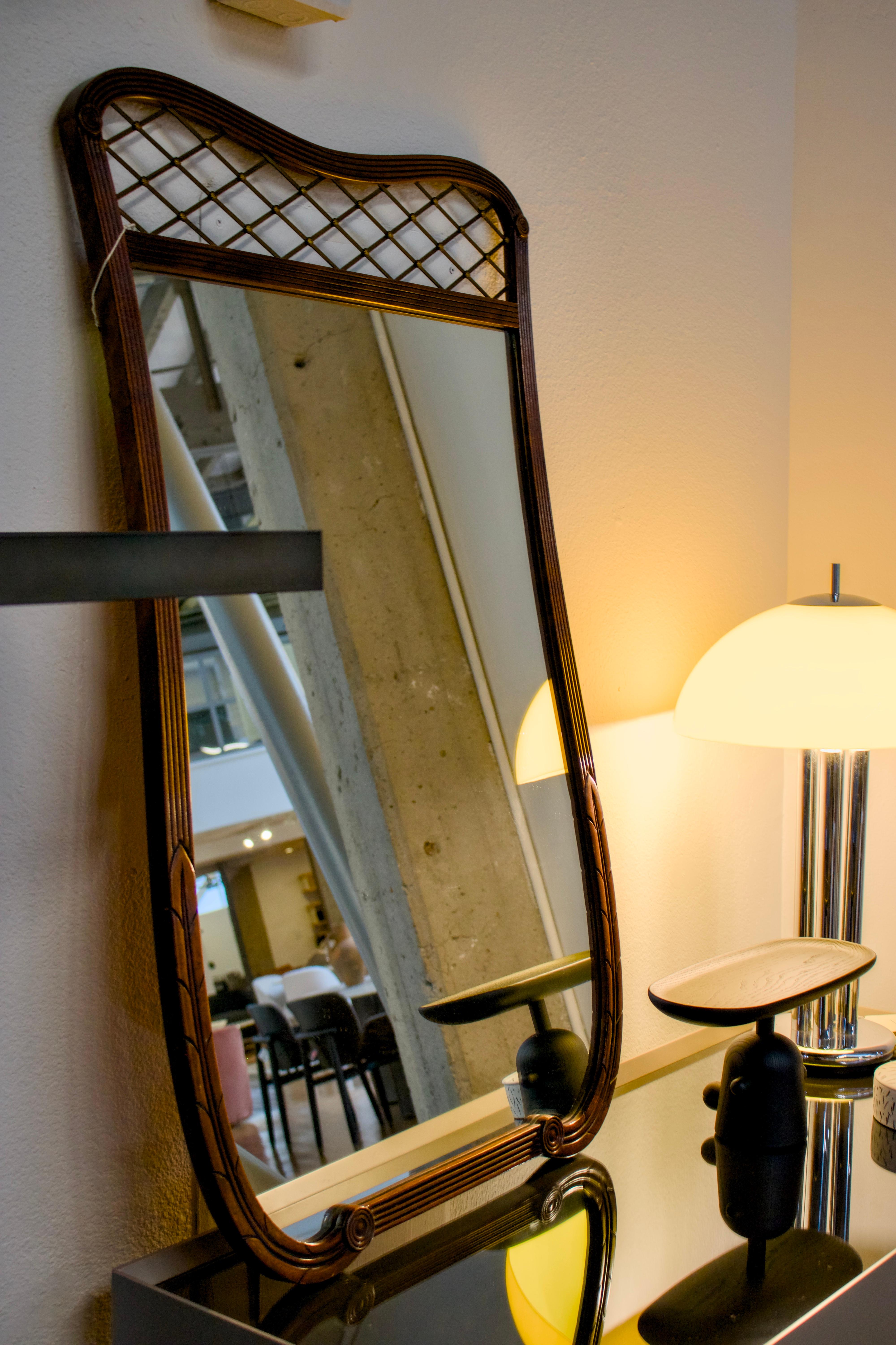 Exceptionnel miroir incurvé en bois, avec des détails de treillis méticuleux et des bordures cannelées raffinées. La silhouette harmonieuse témoigne d'un savoir-faire magistral, tandis que les riches tons de bois créent une présence intemporelle qui