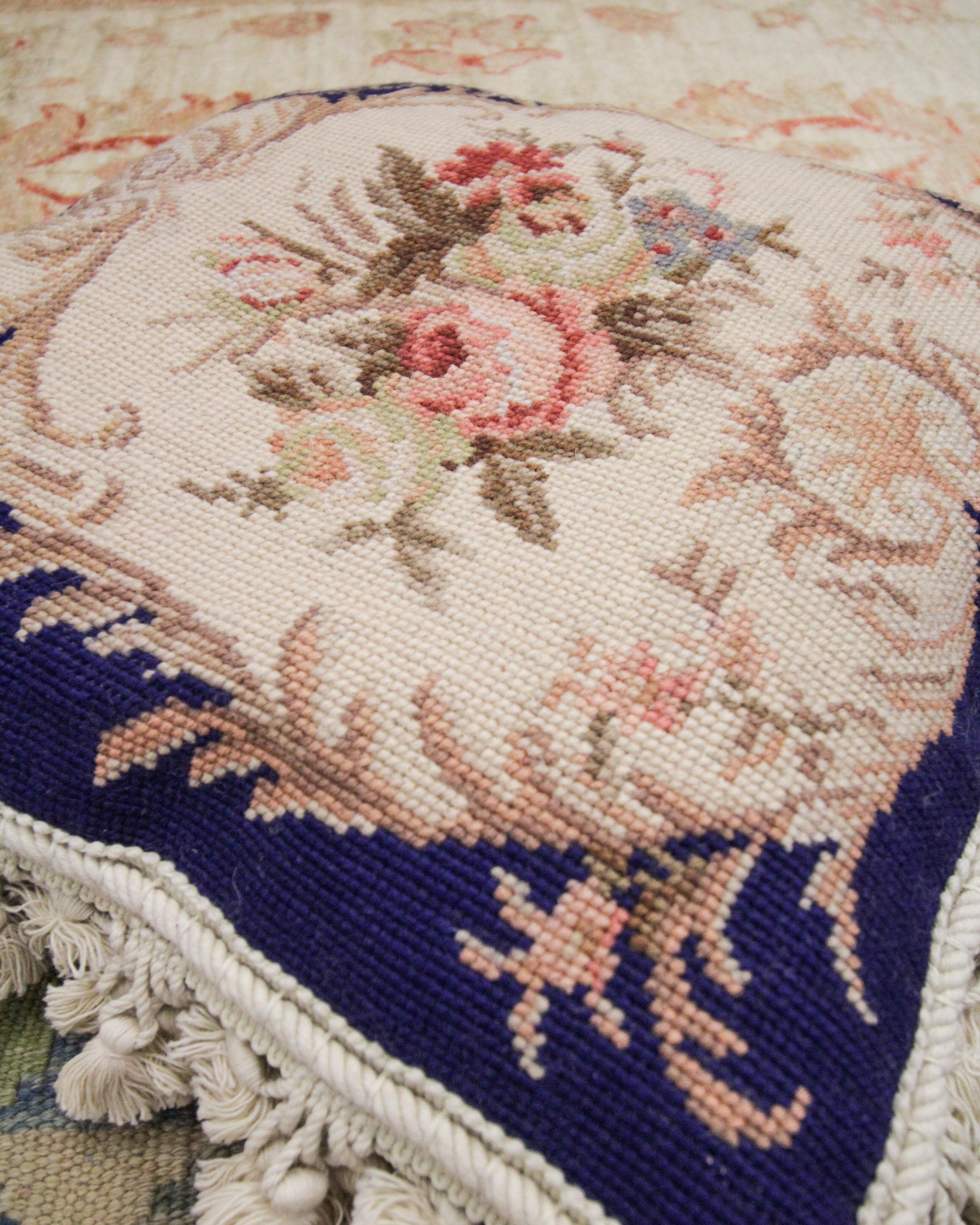 Woven by hand with a classic royal colour palette this cushion is an excellent example of needlepoint cushions from the 1990s. The central design features a cream background woven with an intricate floral design in accents of green, brown and pink.